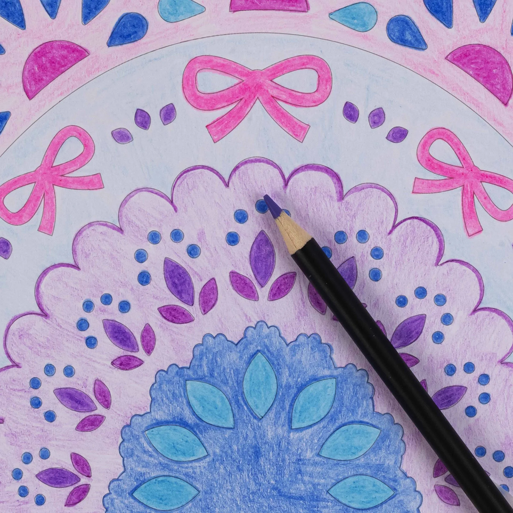 Colorful drawing of floral patterns with pink bows, purple leaves and blue petals, with a black pen resting on top.