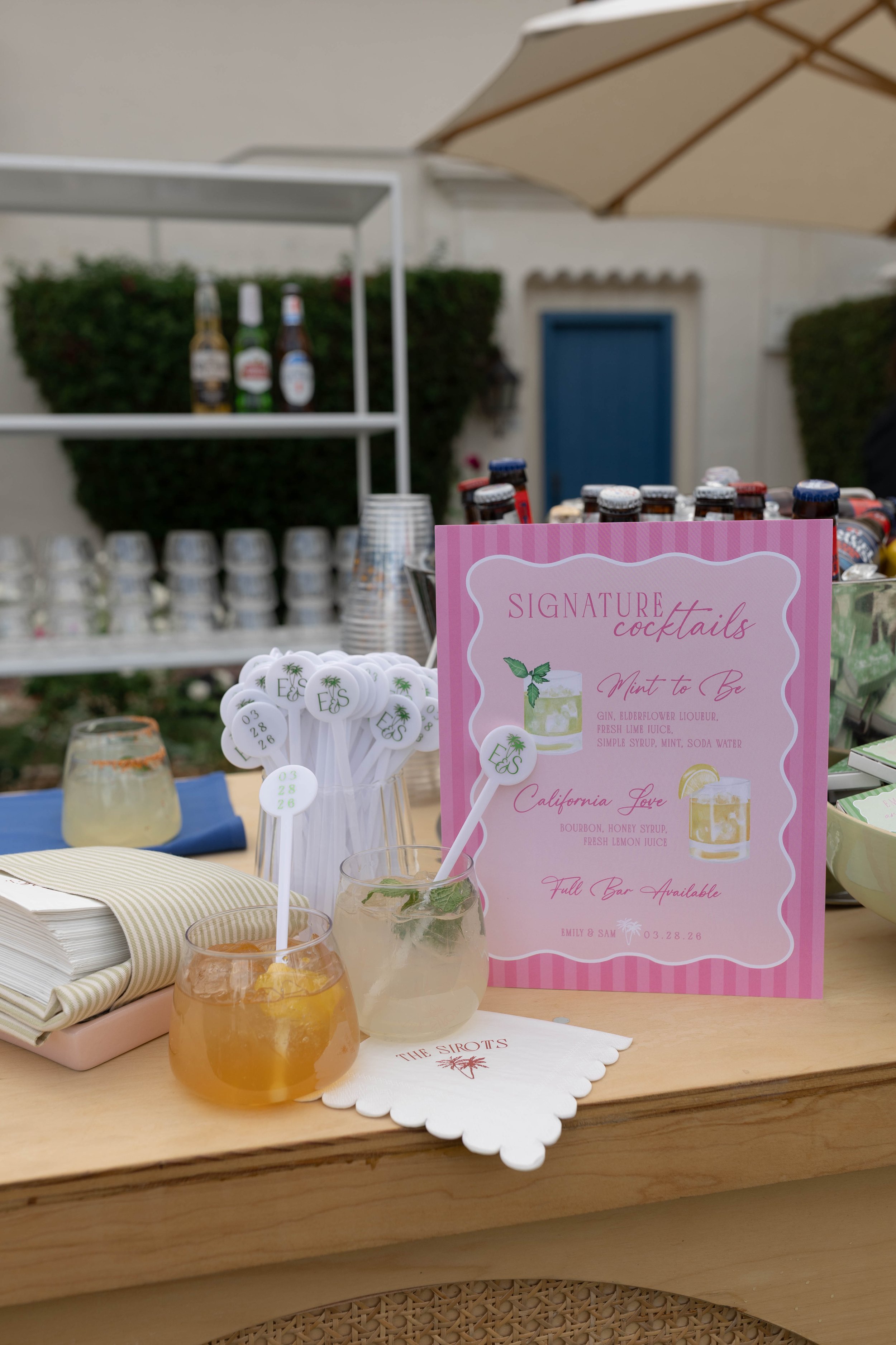 pink striped wedding signature drink sign with cocktail stirrers and napkins