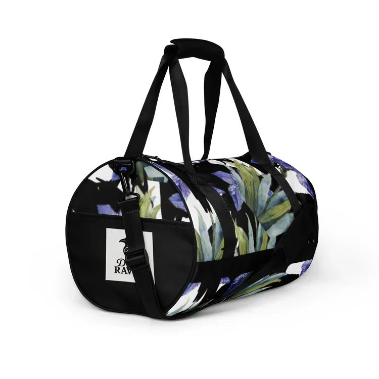 A duffle bag with a floral print pattern, black straps, and a logo patch on the side, placed against a white background.
