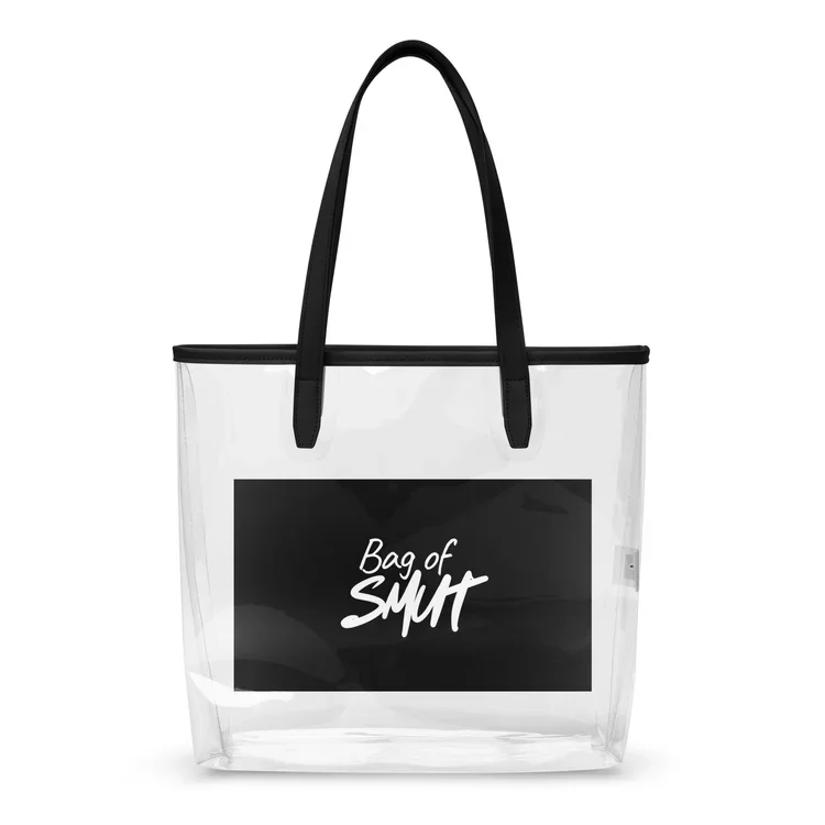 A transparent tote bag with black handles and a black patch on the front that says "Bag of S**t" in white handwritten font.
