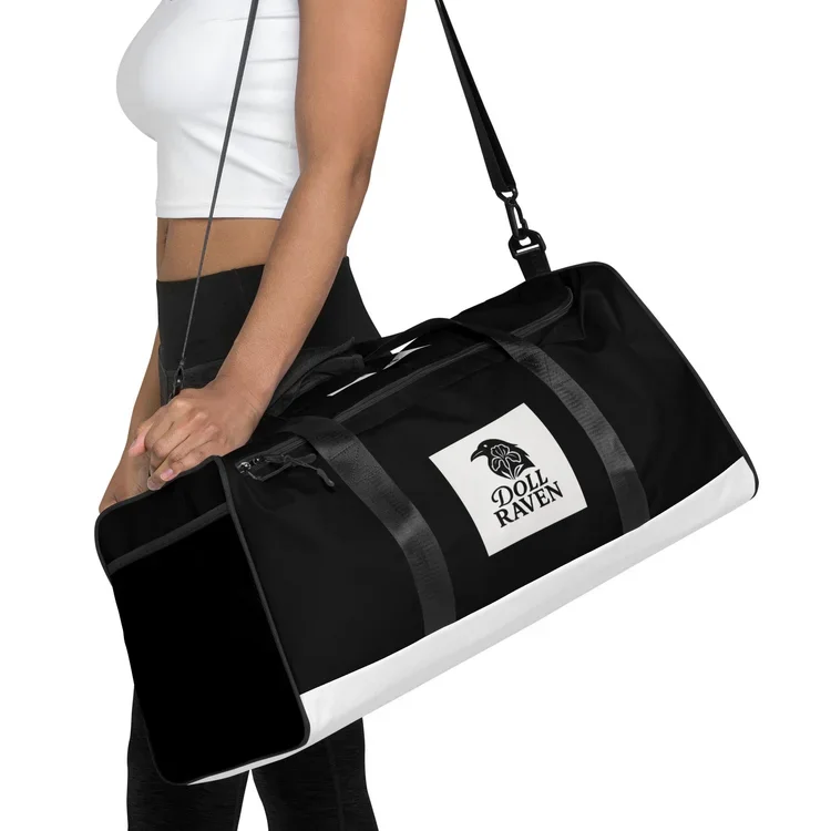 A woman holding a black and white duffel bag with a Doll Raven logo, wearing a white crop top and black pants.