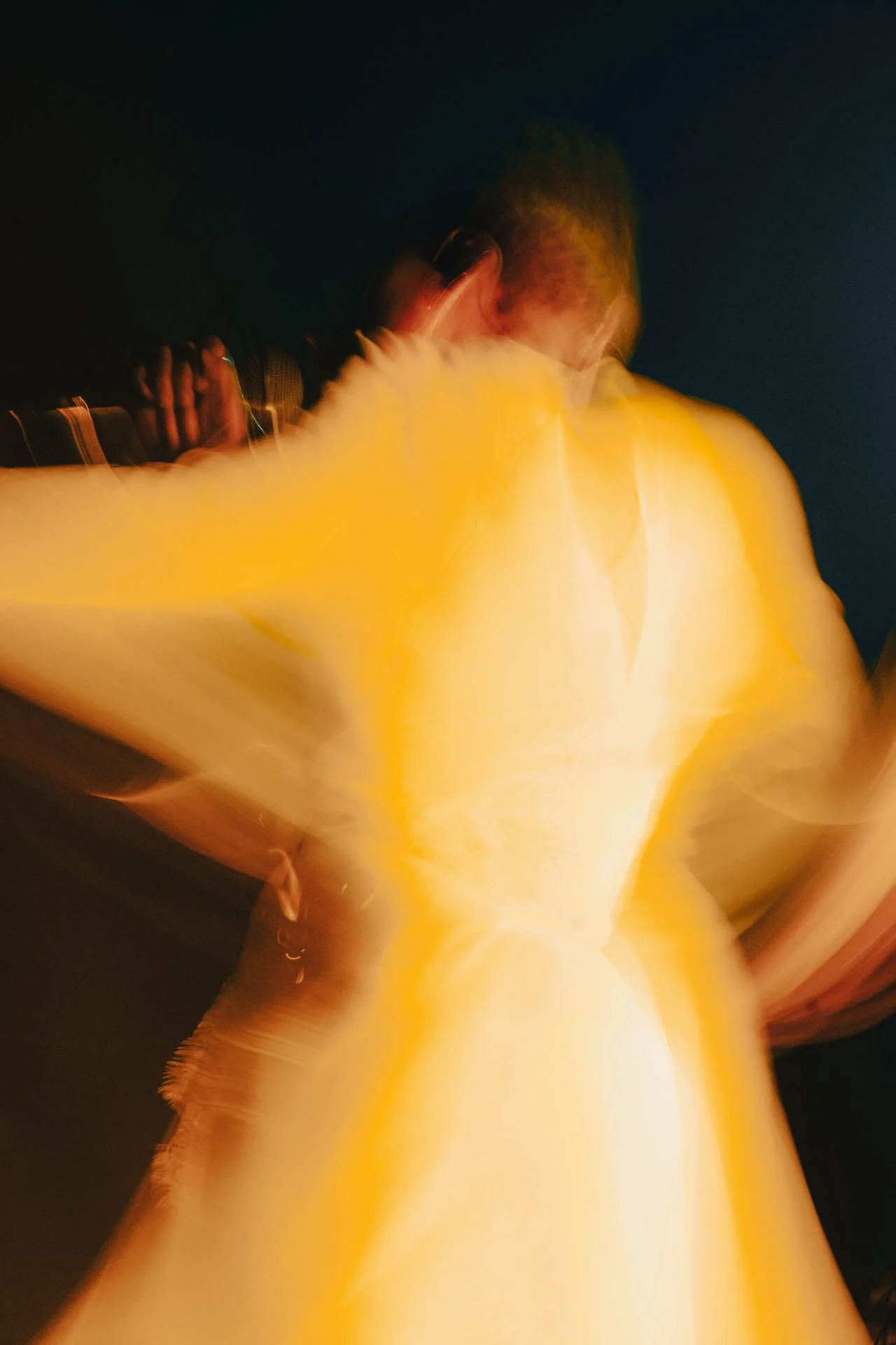 Une personne portant un t-shirt blanc devant un fond sombre, prise avec un effet de mouvement ou de flou, créant une impression de dynamisme et de flou artistique.