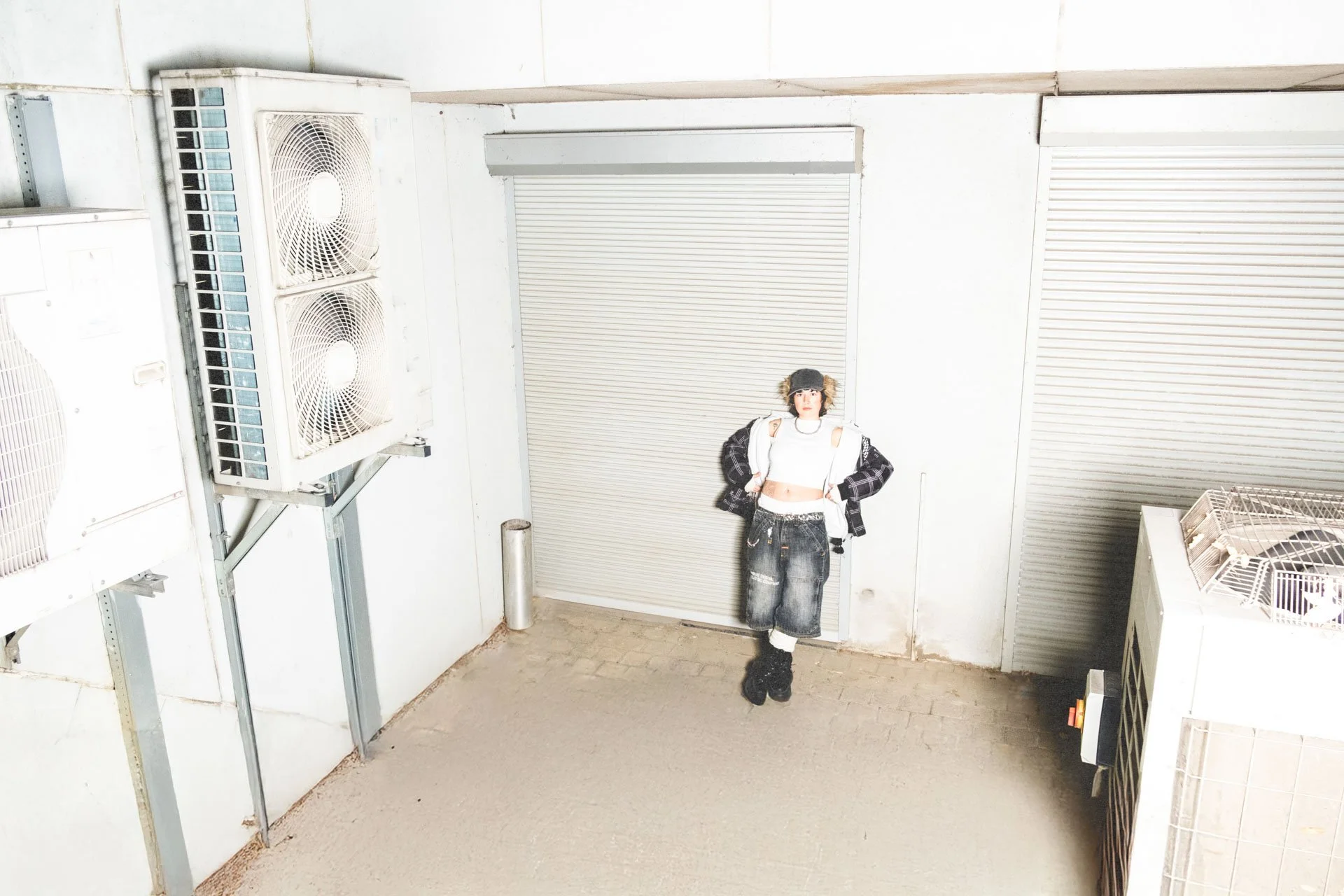 Jeune femme posant dans une pièce avec des portes métalliques roulantes et des appareils de ventilation