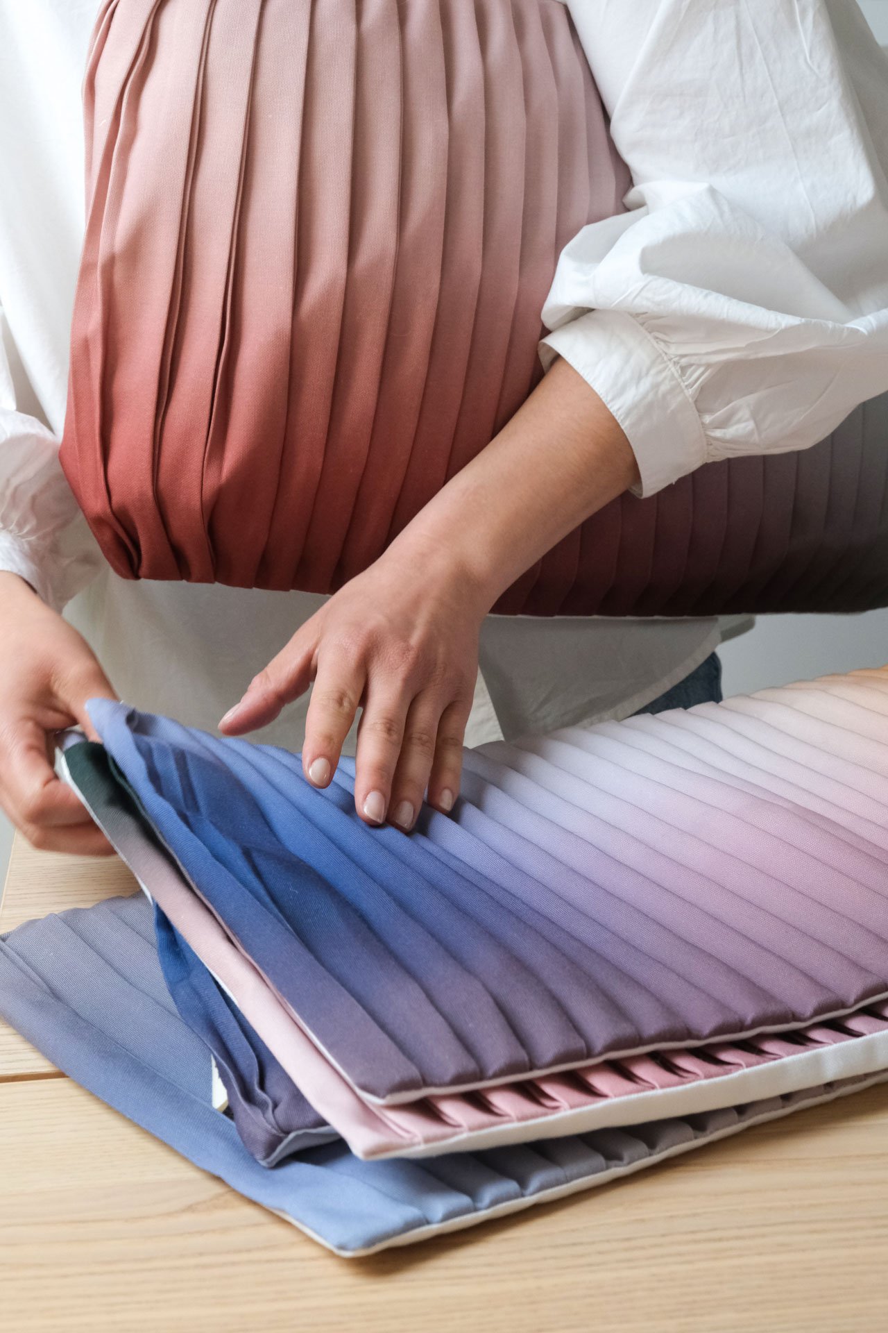 Personne montrant des échantillons de tissus plissés de différentes couleurs.