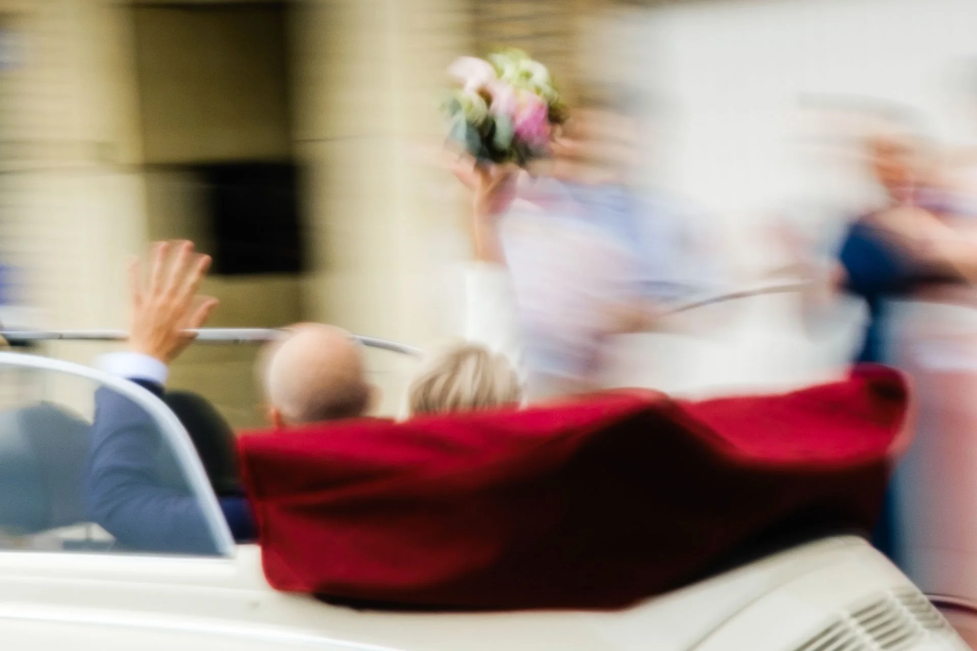Une cérémonie ou un événement officiel avec des personnes assises, une personne en costume saluant, quelques personnes en arrière-plan, ambiance floue