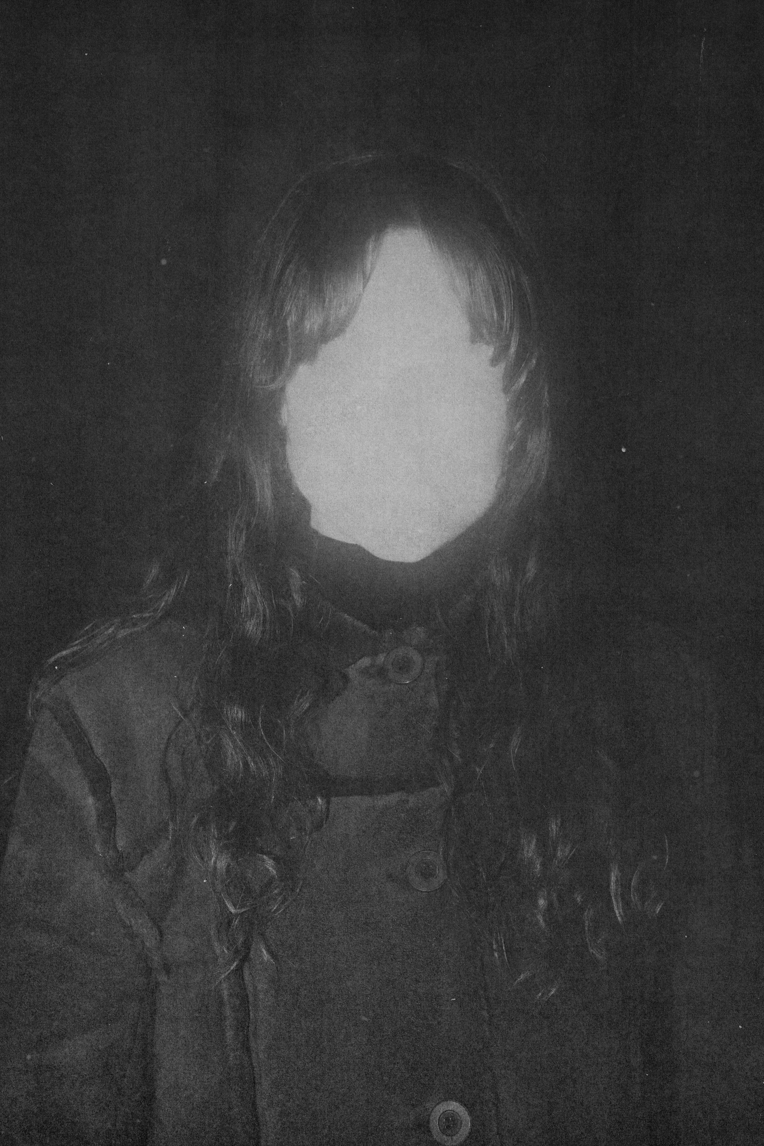 Portrait en noir et blanc d'une femme avec de longs cheveux bouclés, portant une robe avec des boutons.