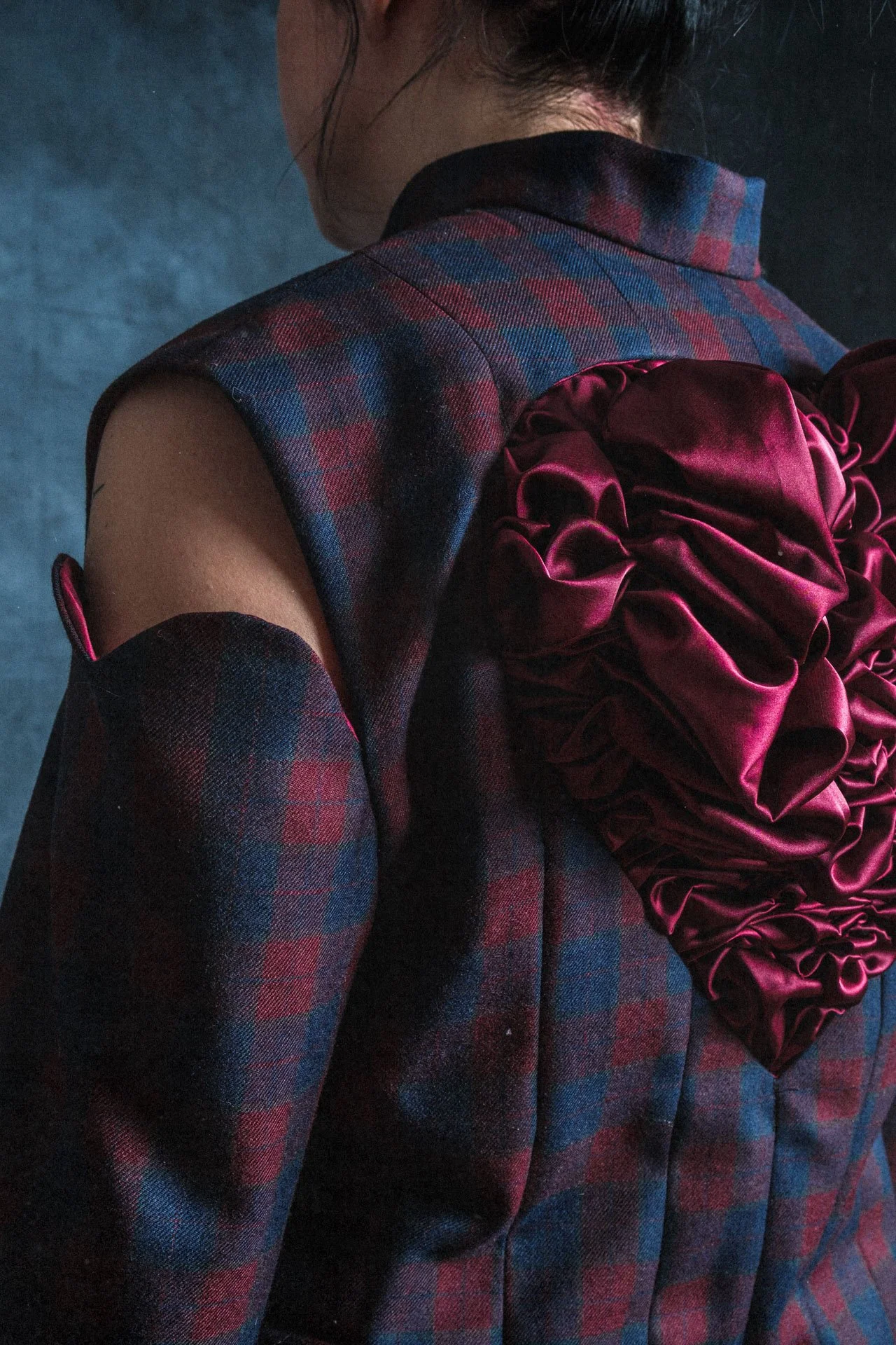 Femme portant une veste en tartan avec un faux porte-jarretelles en satin rouge avec des volumineux nœuds en satin rouge