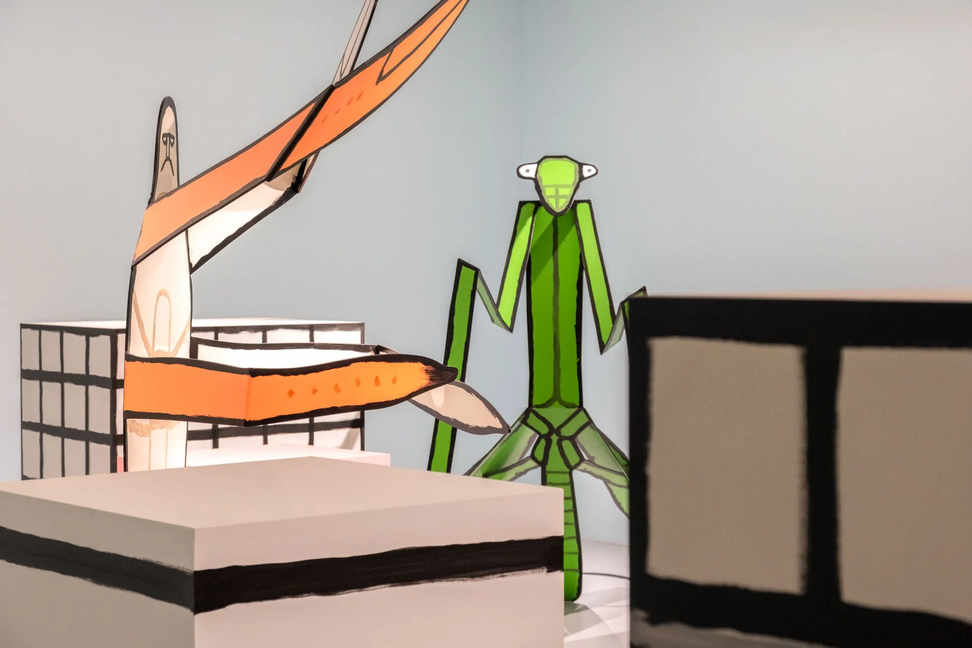 Illustration de dessins en papier représentant une ville avec un bâtiment, une main et un oiseau vert dans un style cartoon.