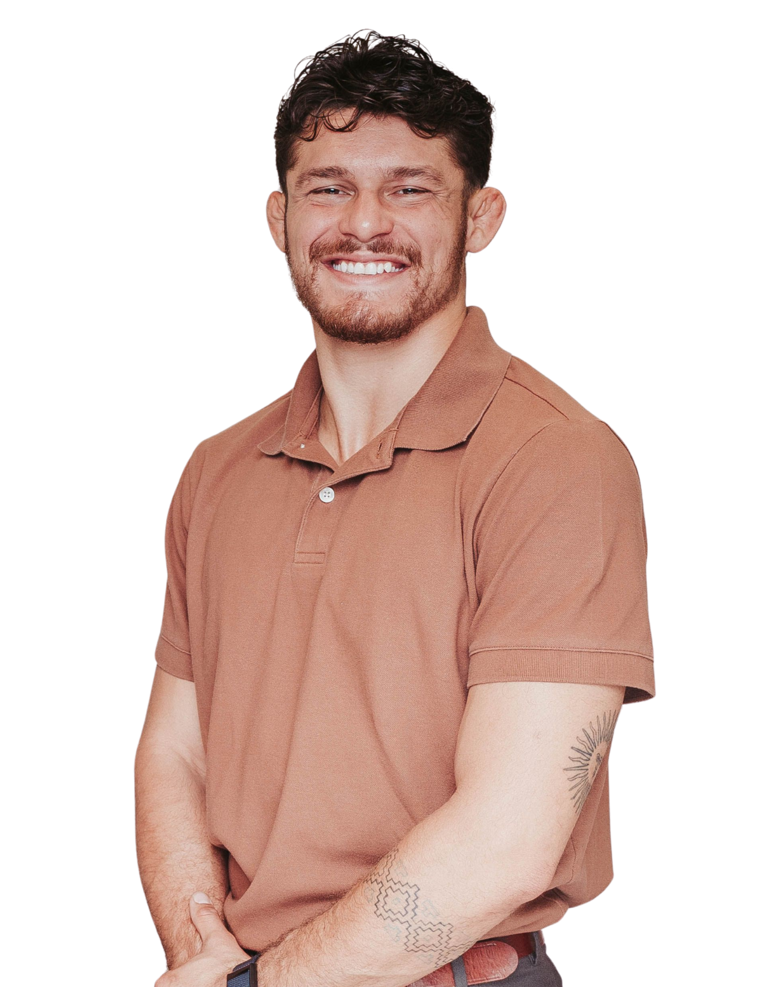 A smiling young man with dark hair and a beard, wearing a light brown polo shirt, standing with arms crossed and looking at the camera.