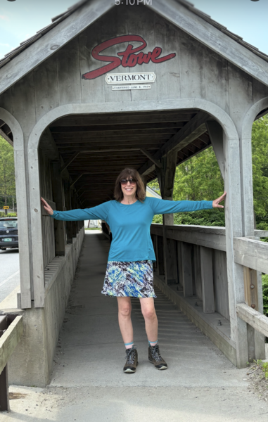 Lisa smiling while standing on a covered bridge in Vermont