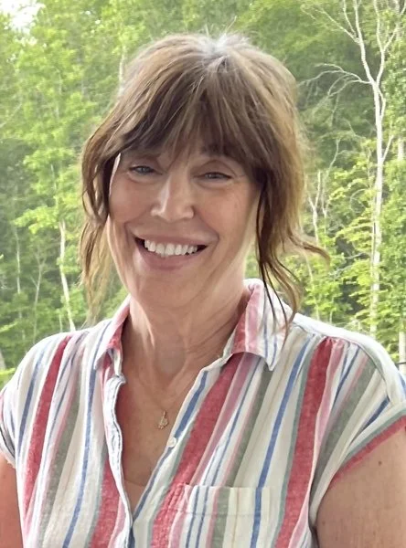 A headshot of Lisa France smiling with a wooded background.