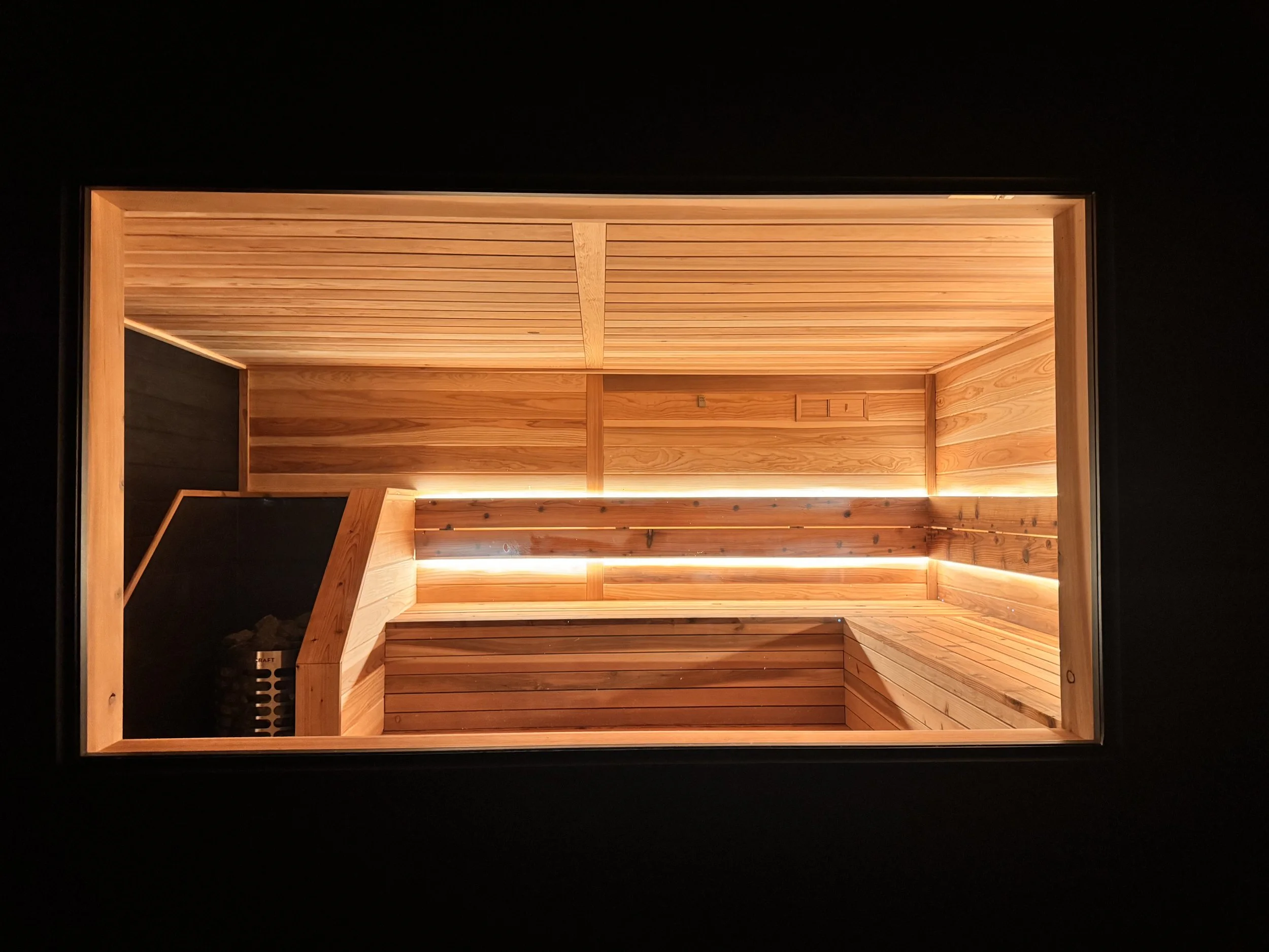 Interior of a wooden sauna with bench seating and warm lighting.