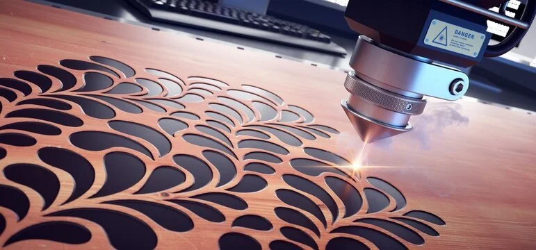 A laser cutting machine cutting intricate shapes into a sheet of metal, with sparks flying from the cutting point.