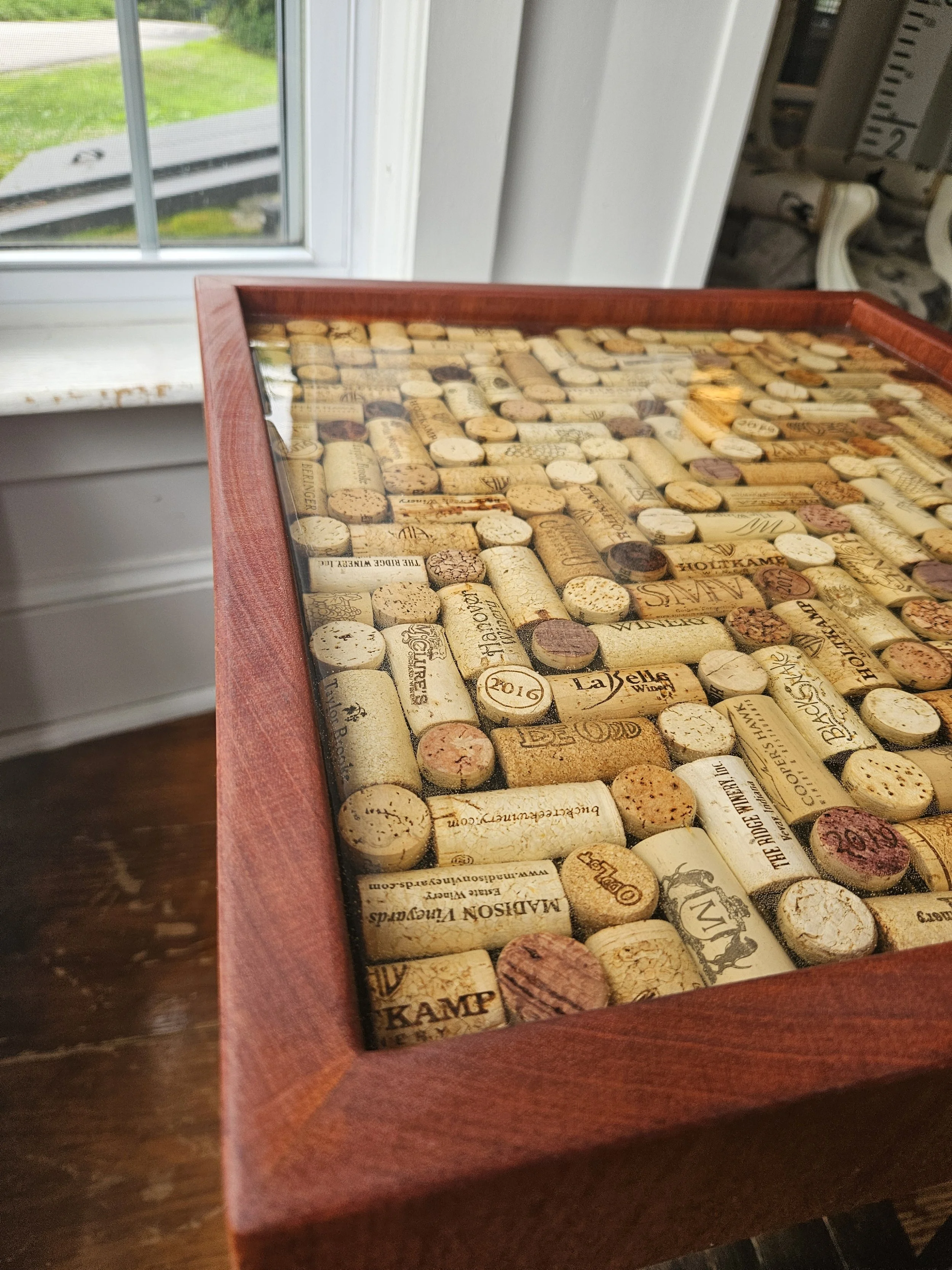 A collection of wine corks encased in epoxy within a wooden table top.