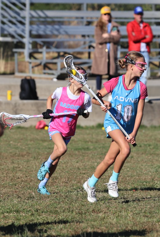 Female lacrosse players running in a fast-paced Super 6s girls lacrosse tournament game at a Tenacity event