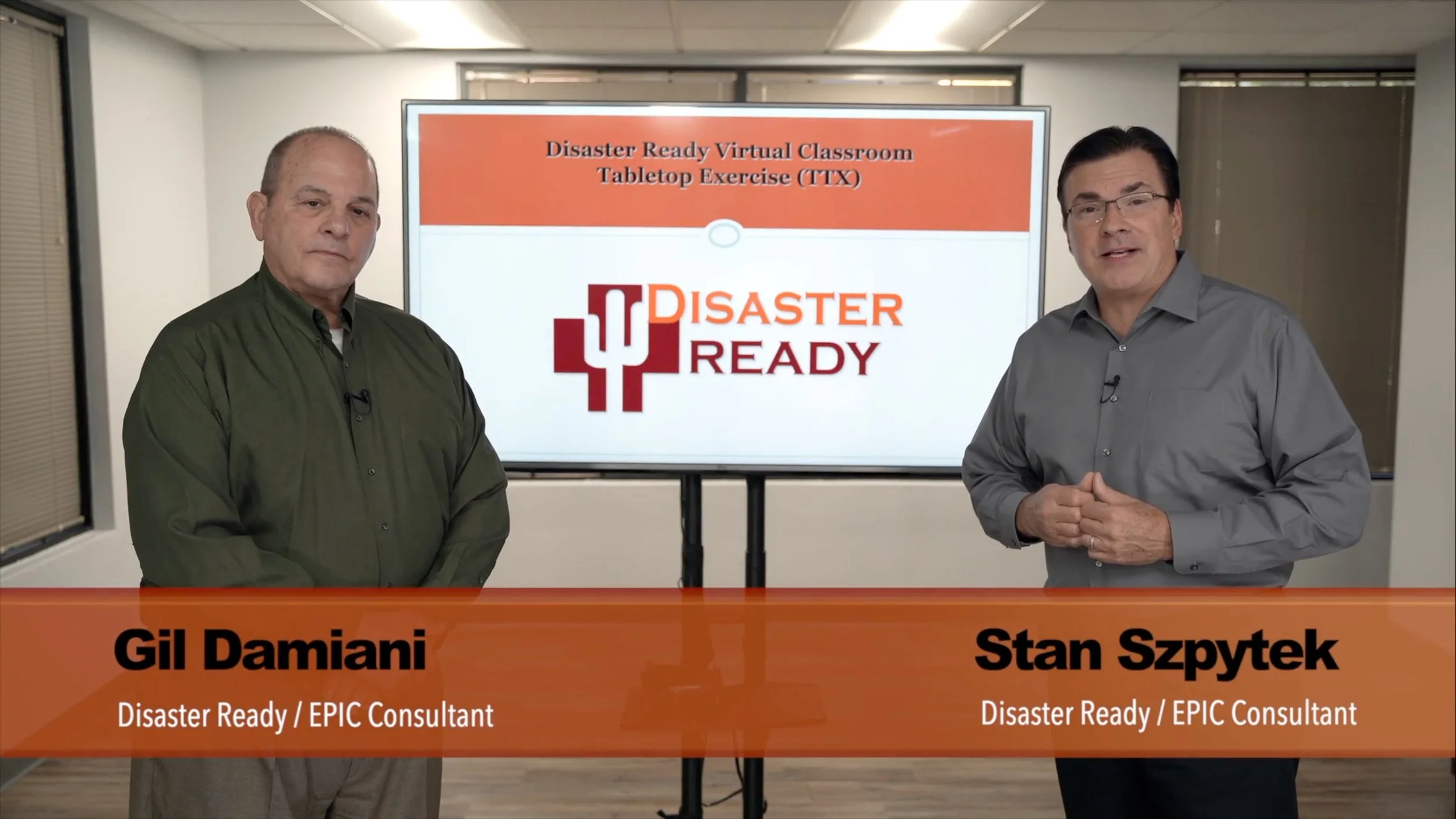 Two men standing in front of a large screen displaying a presentation slide titled "Disaster Ready Virtual Classroom Tabletop Exercise (TTX)." The man on the left is wearing a green shirt, and the man on the right is wearing a gray shirt. A banner at the bottom shows their names: Gil Damiani and Stan Szpytek, both labeled as Disaster Ready / EPIC Consultants.