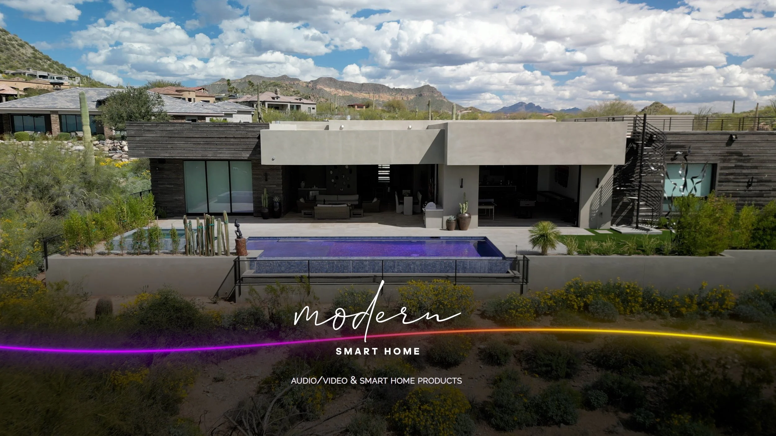 Modern house with a backyard pool, outdoor seating area, and desert landscape, featuring mountains in the background.
