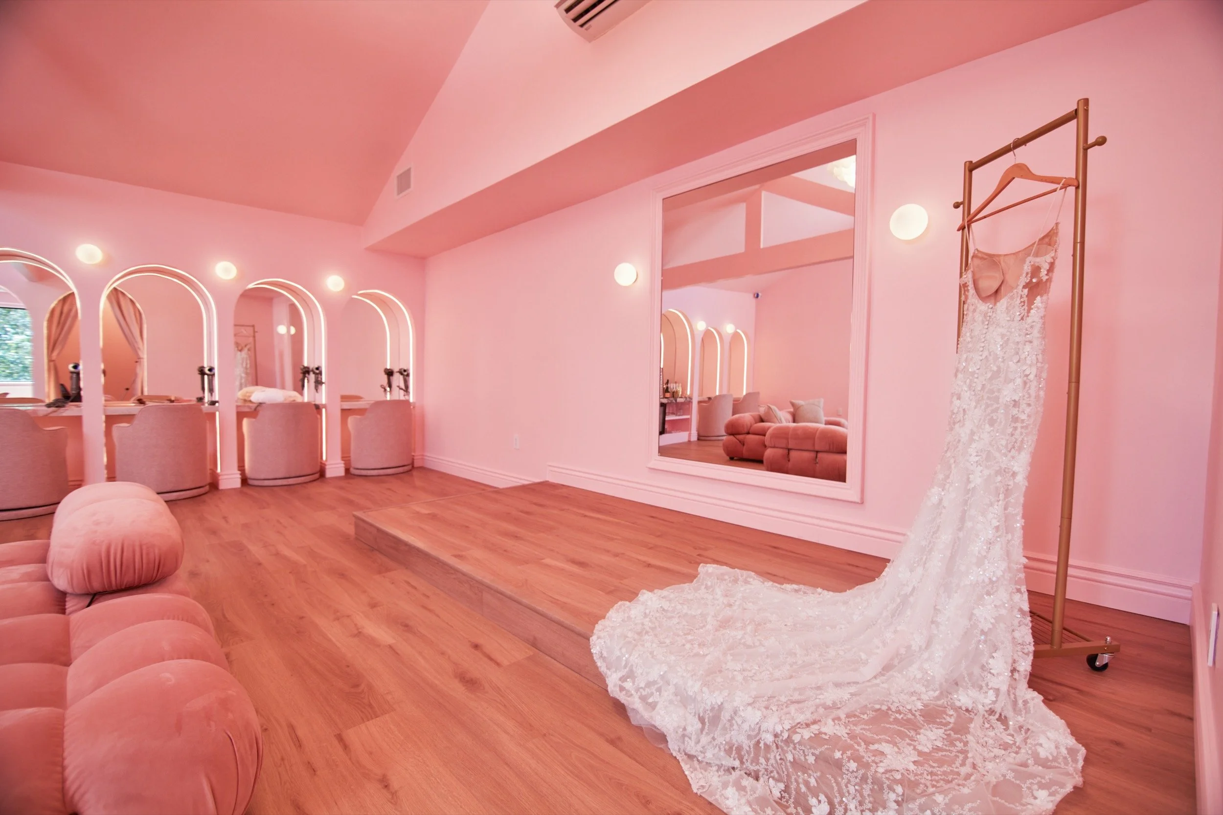 Styling stations with arched mirrors in the Bridal Suite, a wedding gown in the foreground.