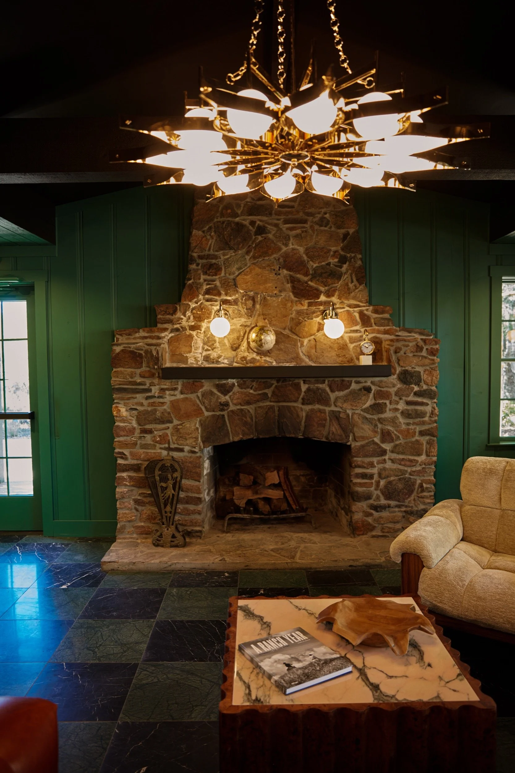 A second native stone fireplace set into green paneled walls.