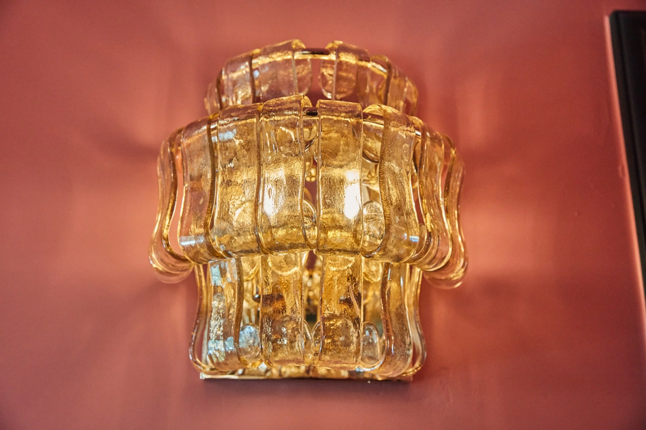 A vintage glass sconce against a pink wall, one of the Art Deco-inspired details throughout the property.