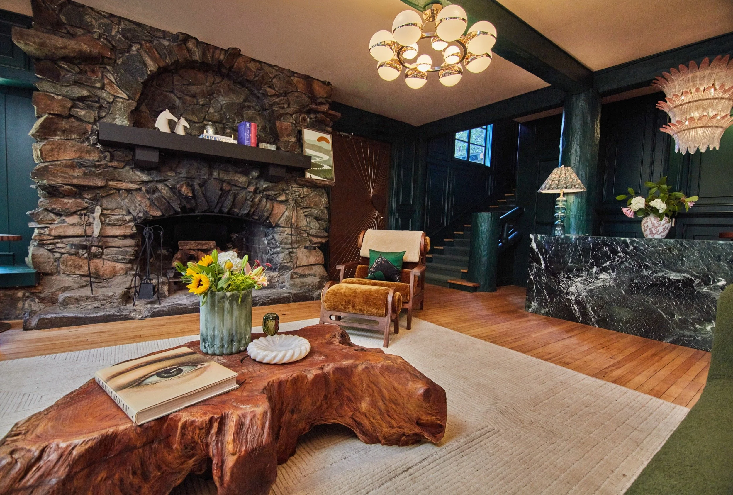 The Lodge lobby, with a native stone fireplace, live-edge wood tables and a globe chandelier.
