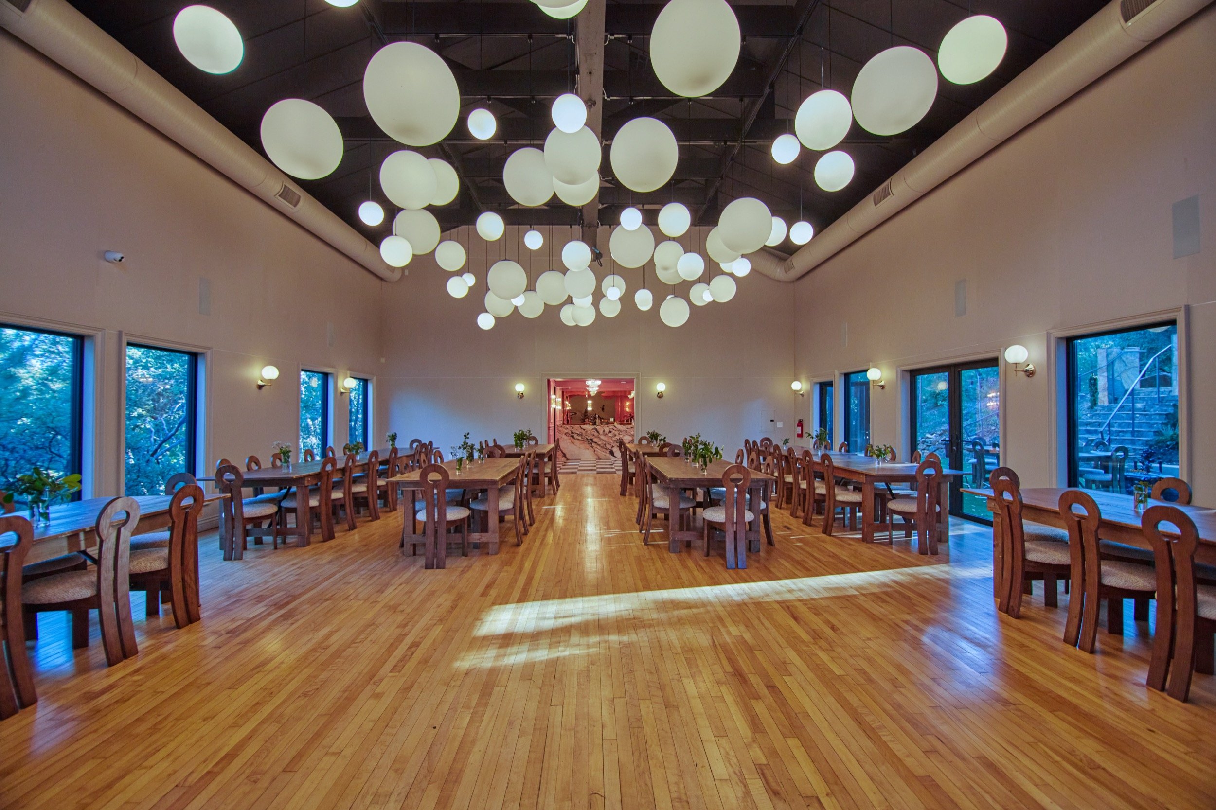 The Event Hall set for a reception, with wood floors and white paper lanterns overhead.