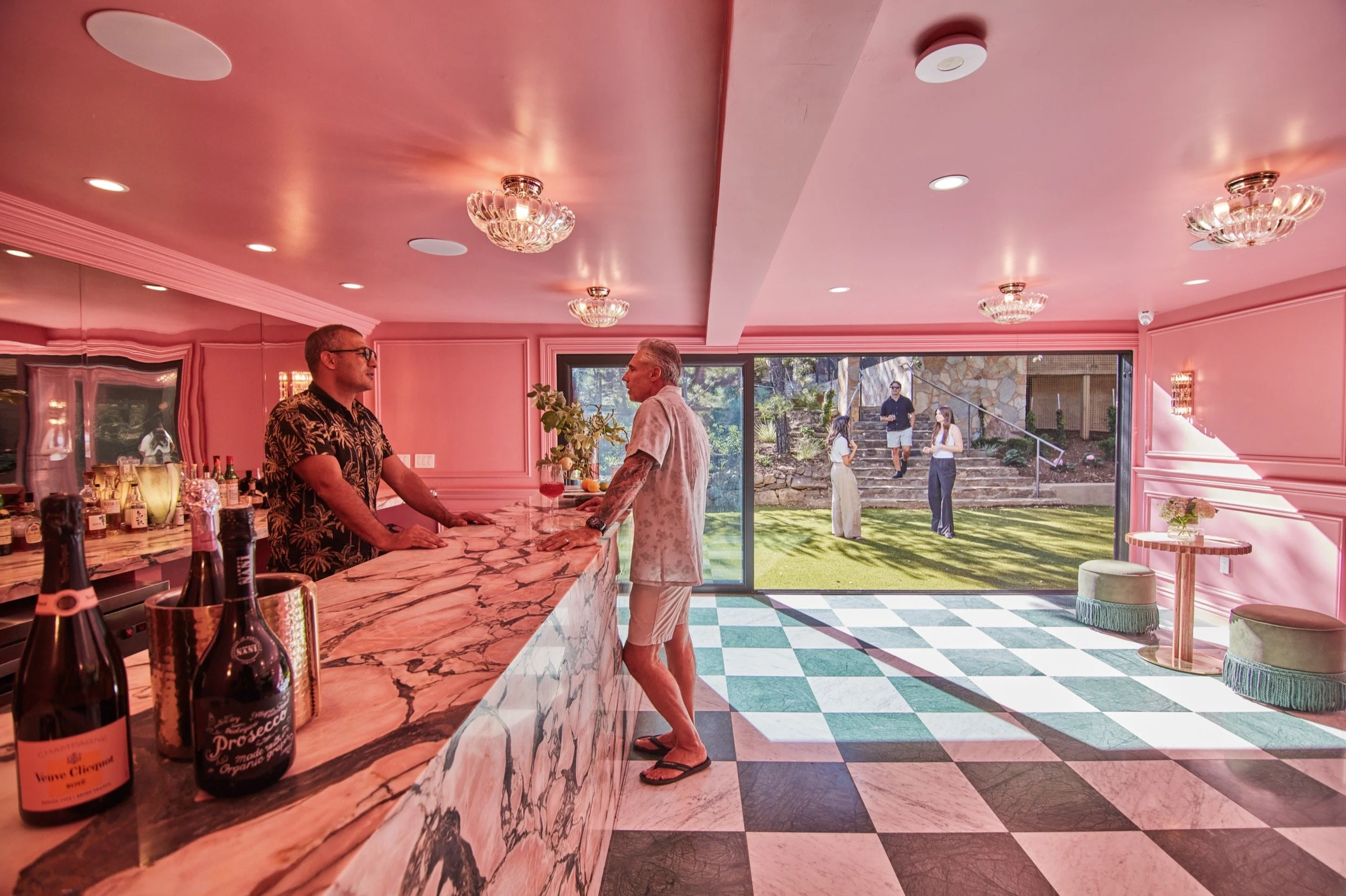 Guests at the Pink Bar, with its marble counter and checkered floor opening onto the lawn.