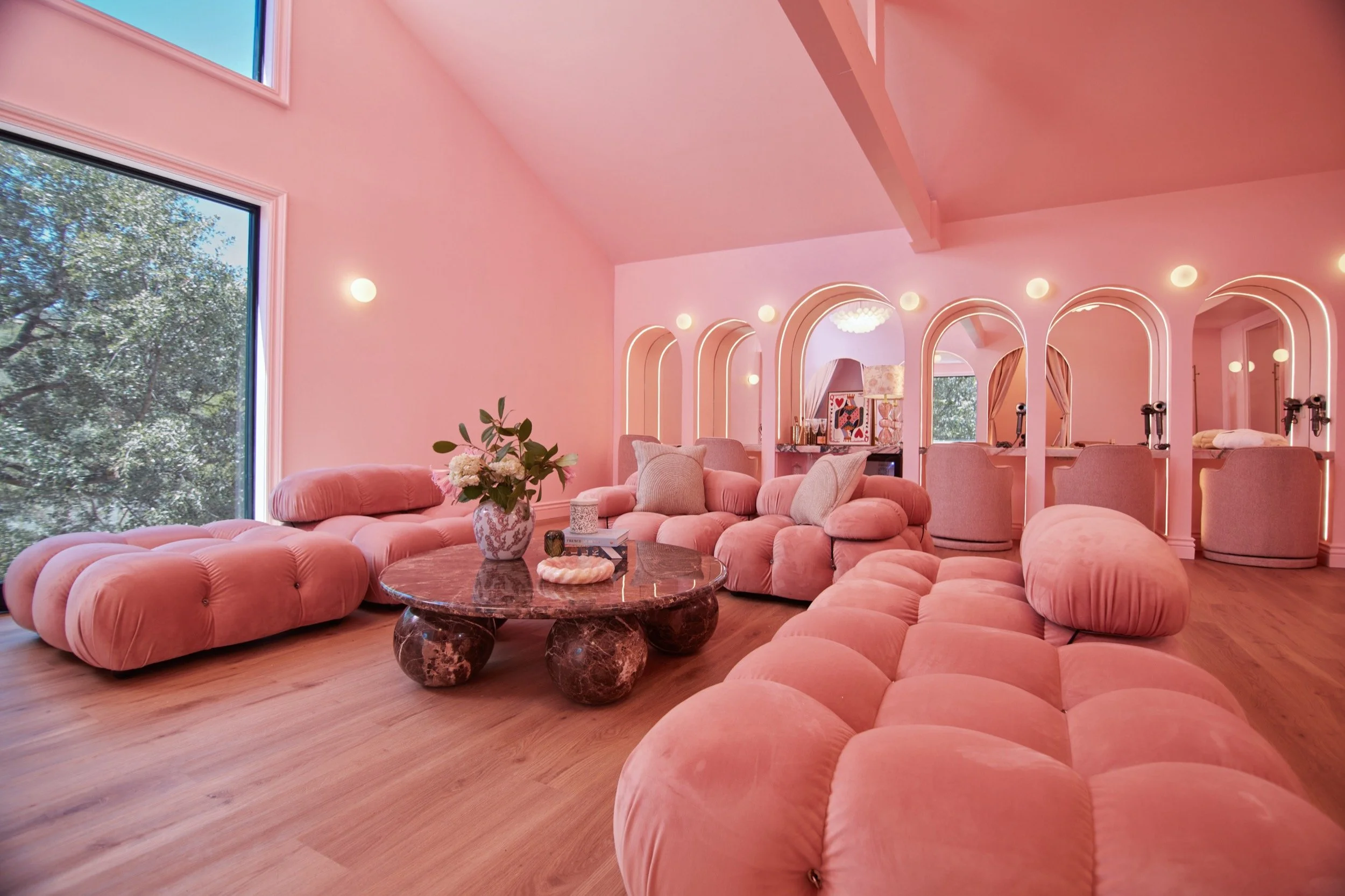 The Bridal Suite lounge, with pink tufted sofas, arched vanity mirrors and a globe chandelier.