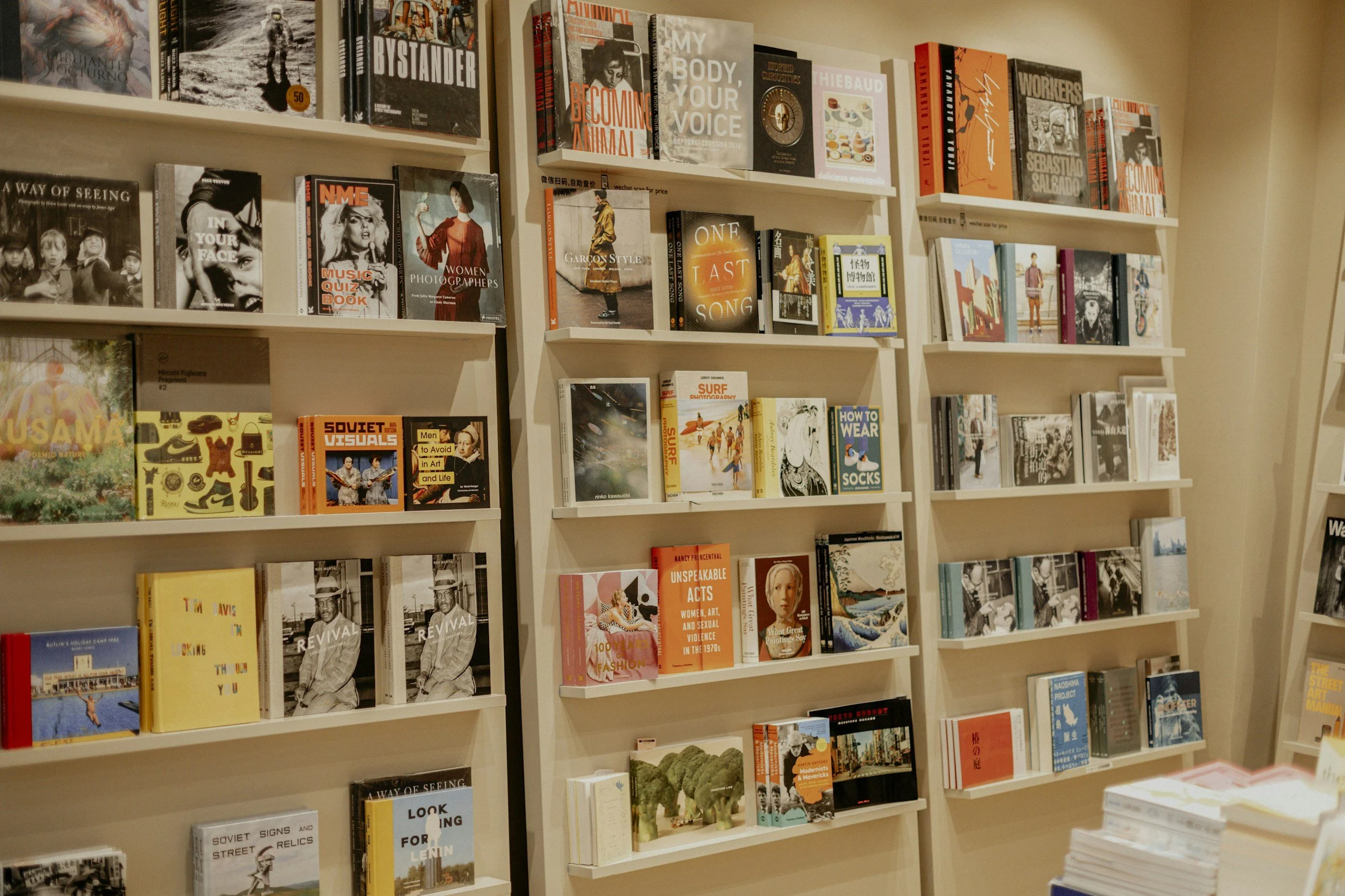 Bookshelves filled with various hardcover and paperback books in a bookstore or library.