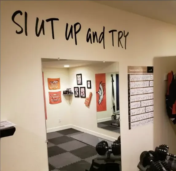Wall inside a home gym with a typo on the wall that says "Slut up and try".