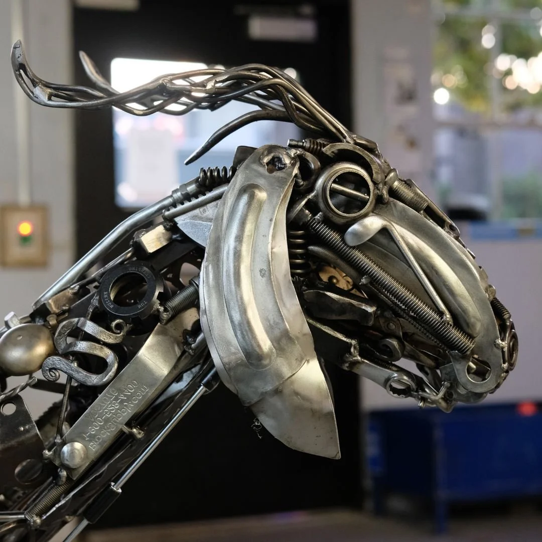 Close-up of a sculpture of a goat made from assorted metal parts and mechanical components.