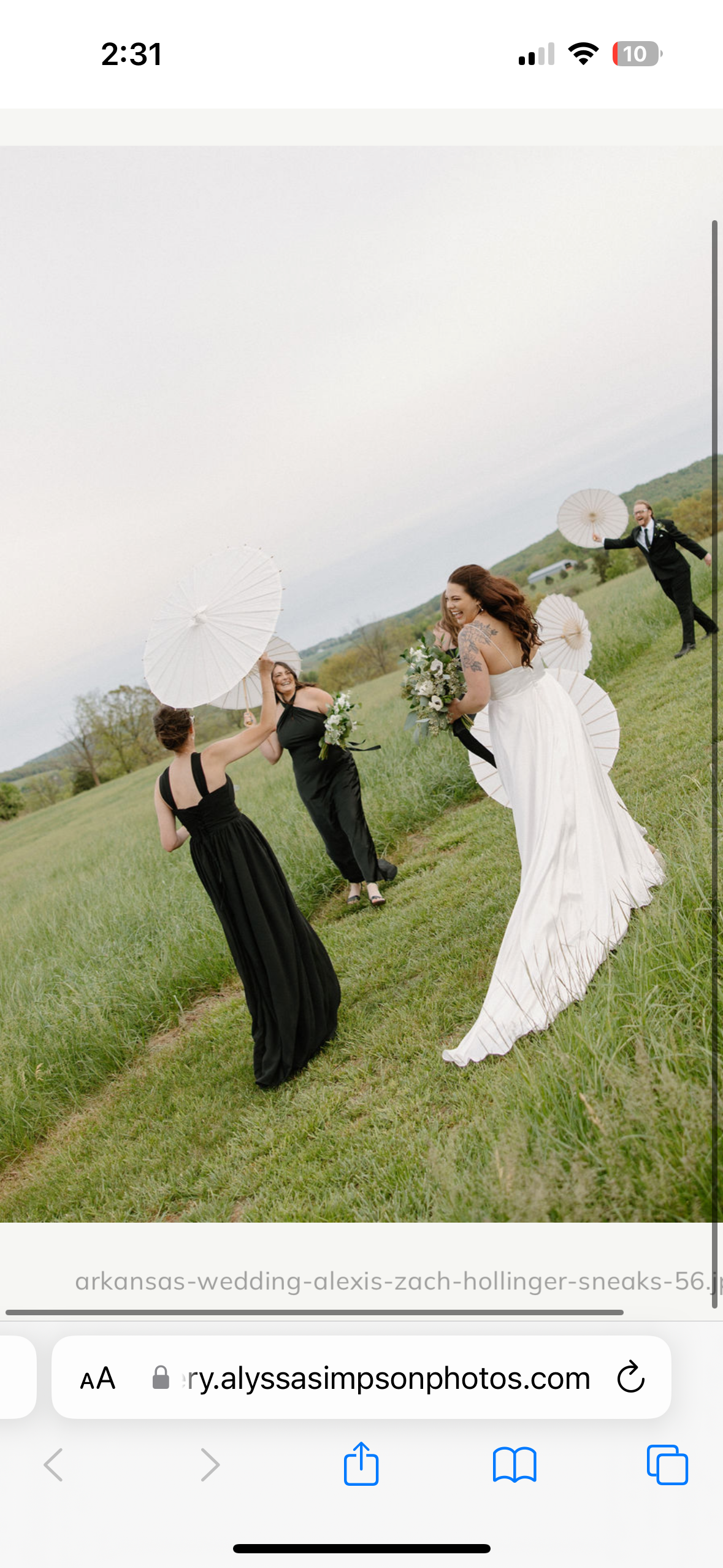 A wedding scene with a bride in a white dress and four bridesmaids in black dresses, all holding white parasols, standing on a grassy field in a rural setting.