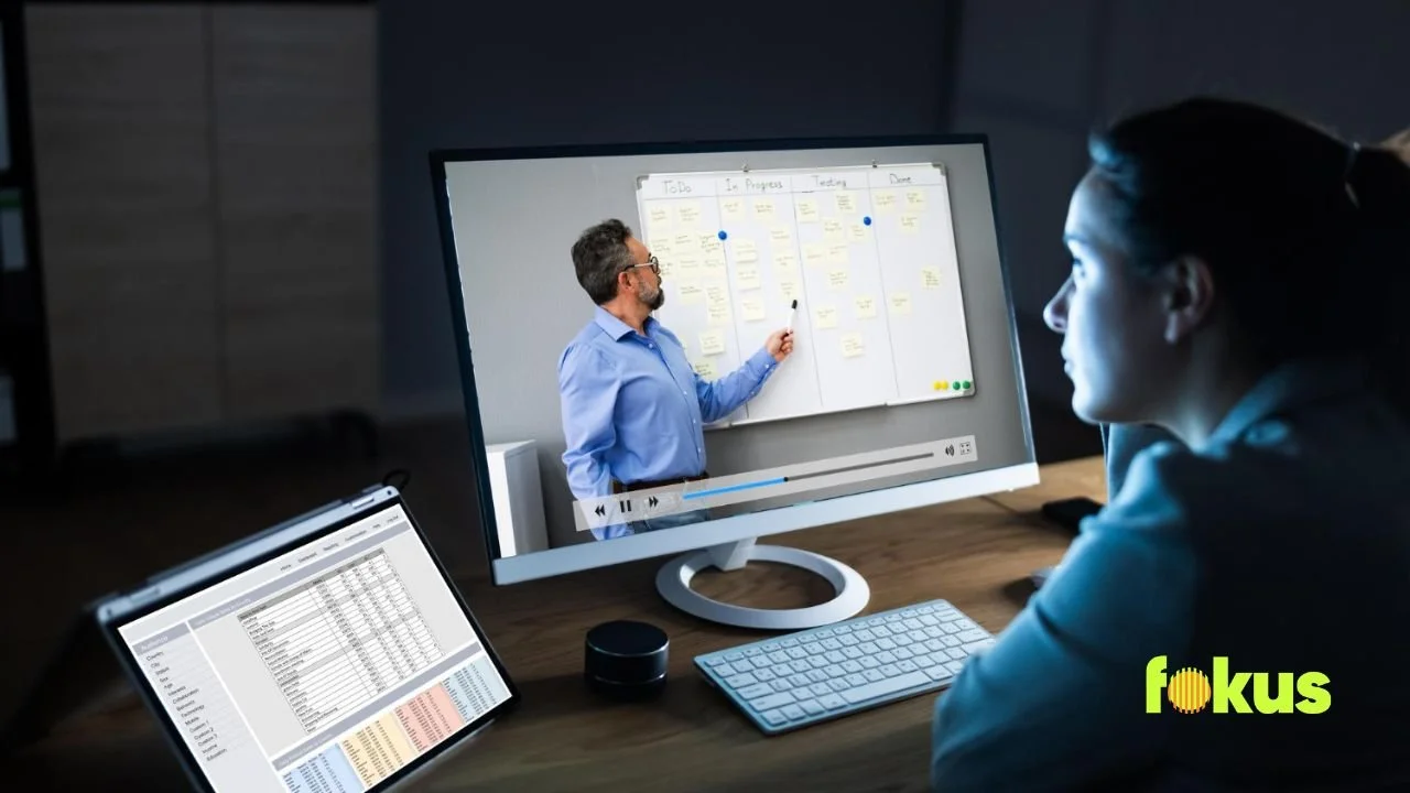 A woman sits at a desk with a computer and whiteboard, focusing on "Instructional Design vs Training Content."