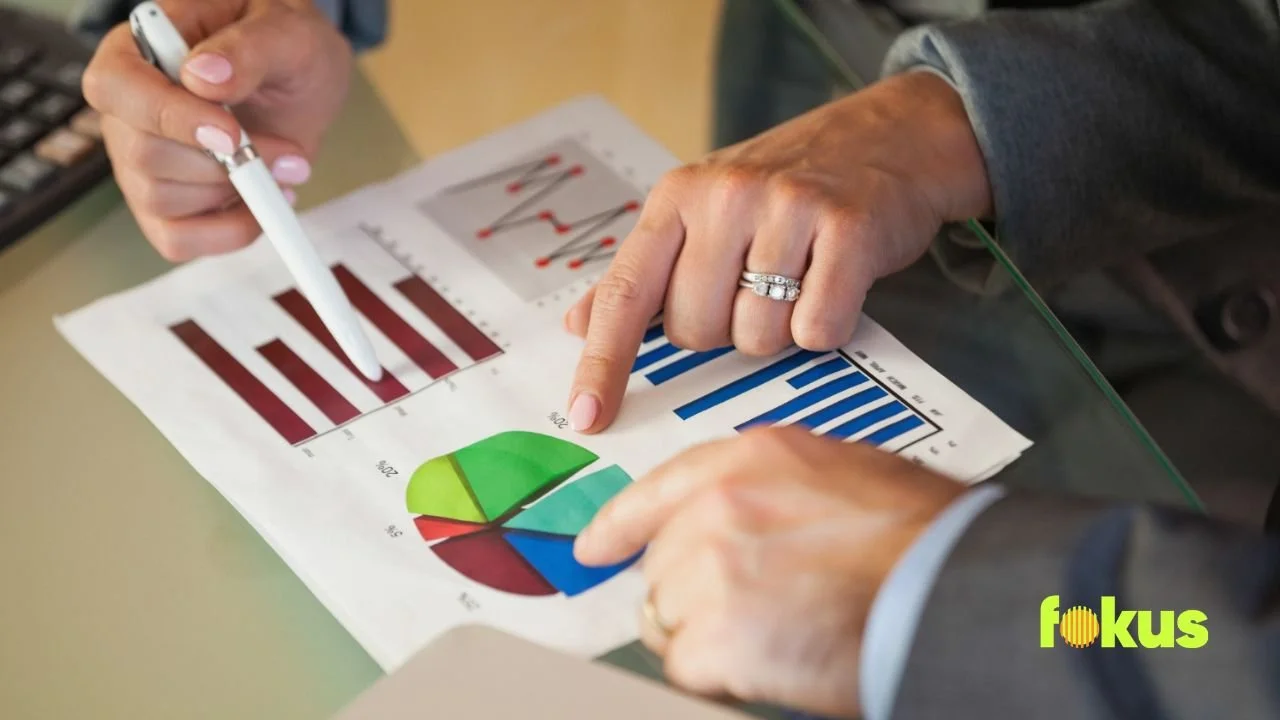 A man and woman analyze graphs on paper, discussing results and setting priorities for their project.