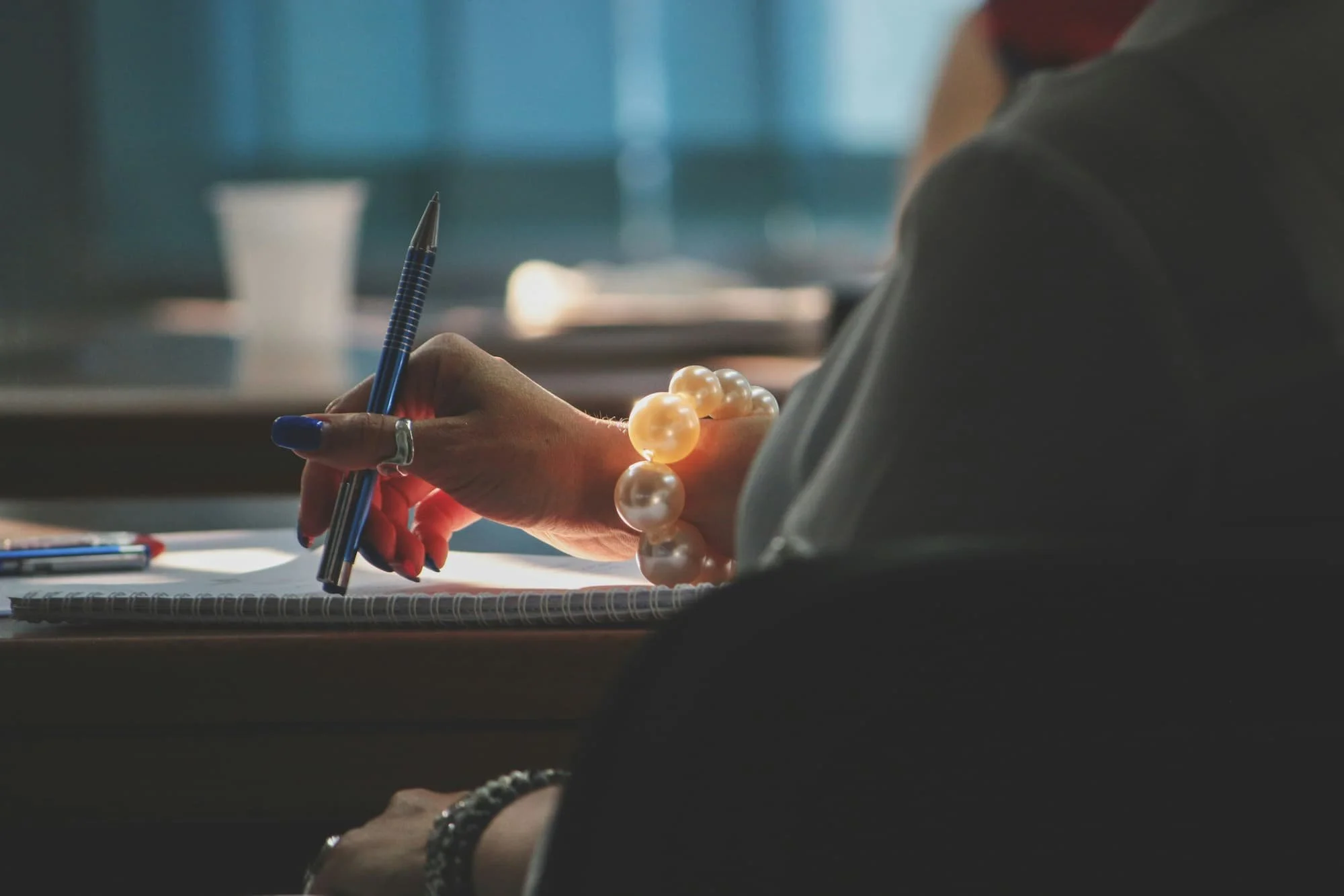 A person writing on a piece of paper with a pen, focused on their task in a well-lit environment..jpg