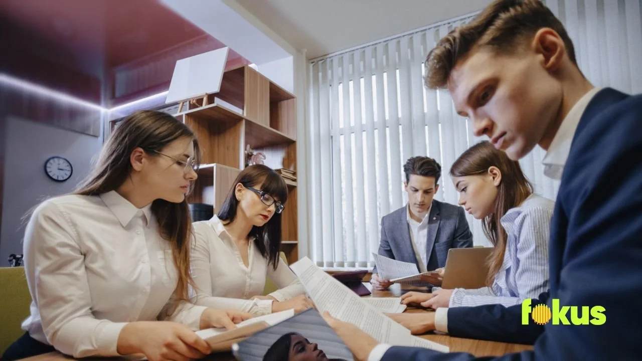 A group of business people seated at a table discussing the Training Needs Assessment Questionnaire for Employees.