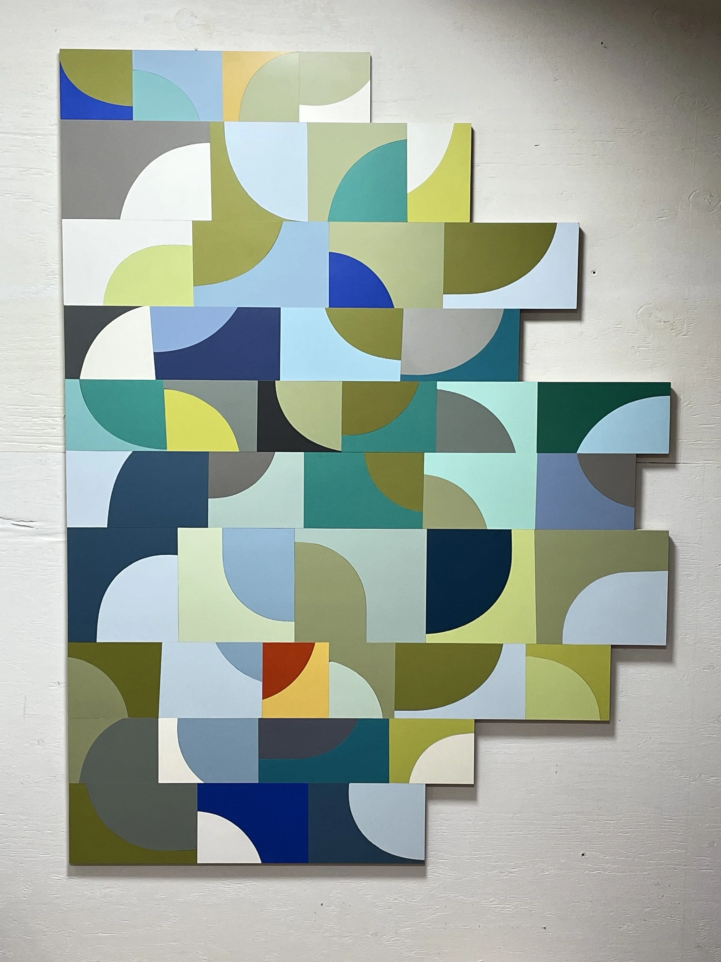 Abstract geometric wall art with various colored rectangular and semicircular shapes arranged in a grid pattern.