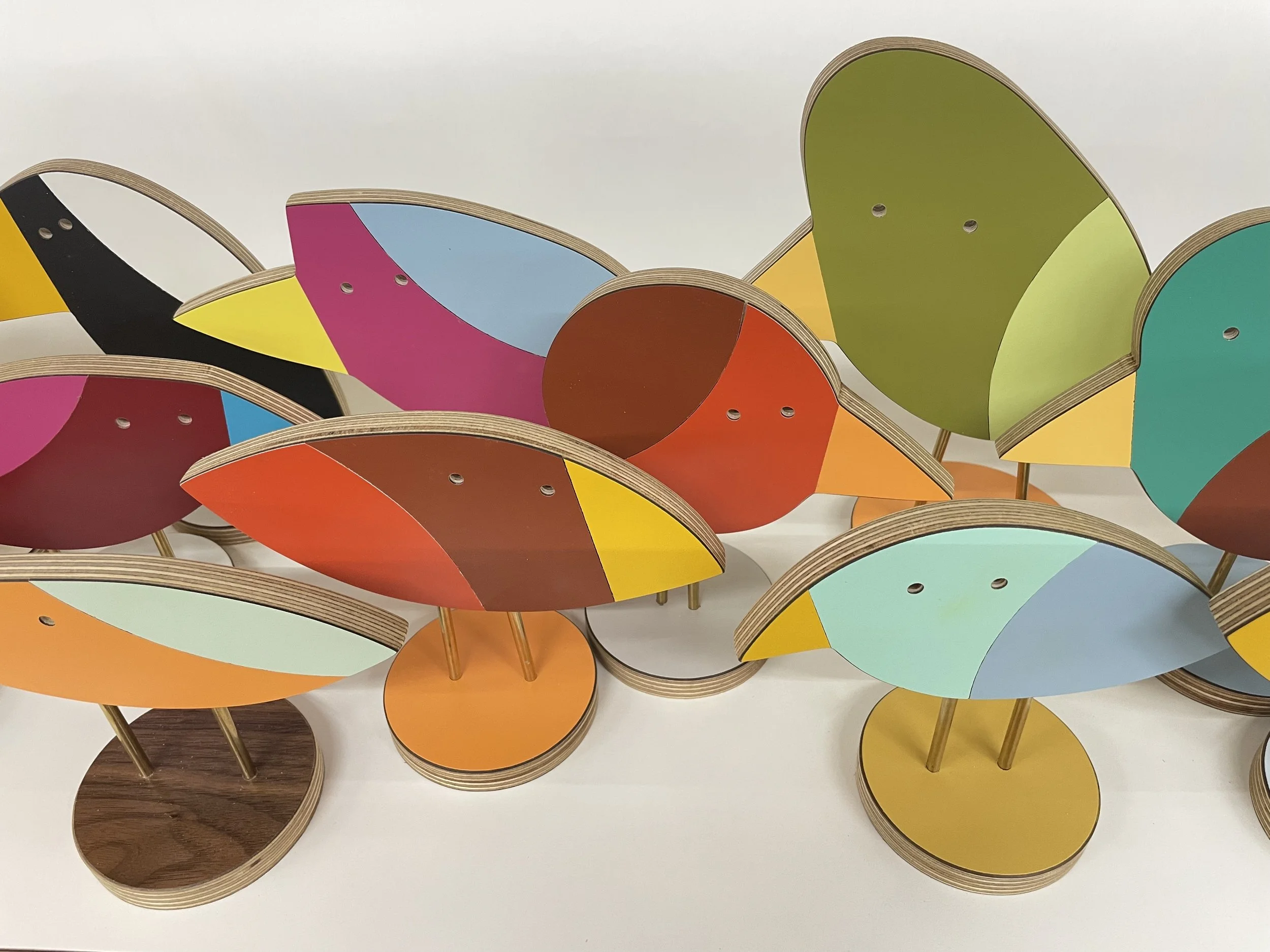 Colorful abstract table shaped like birds with various colored wings and circular bases.