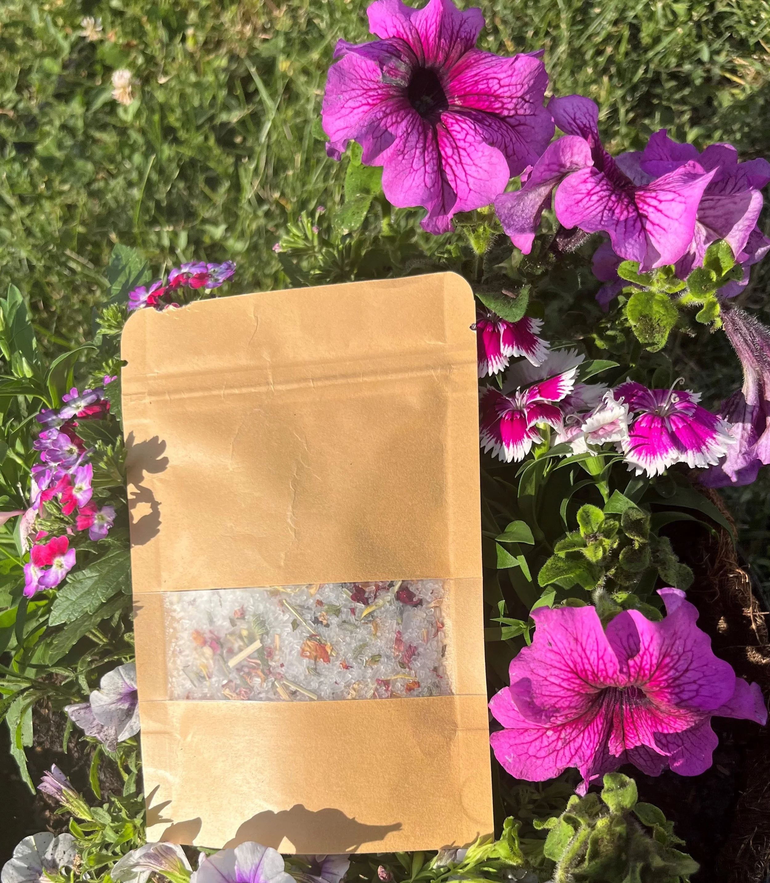 A cardboard seed packet placed among pink, purple, and white flowers in a garden.