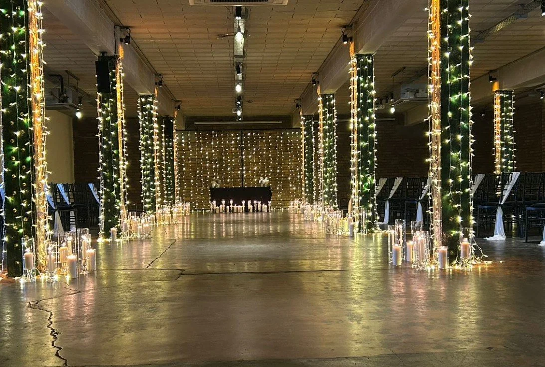 A decorated indoor event space with string lights and candles, possibly set up for a wedding or celebration.