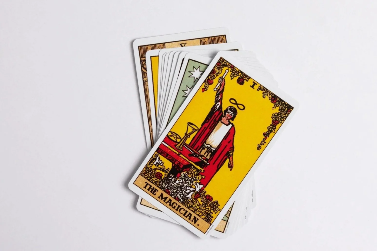 A spread of tarot cards, including The Magician card prominently displayed, with a white background.