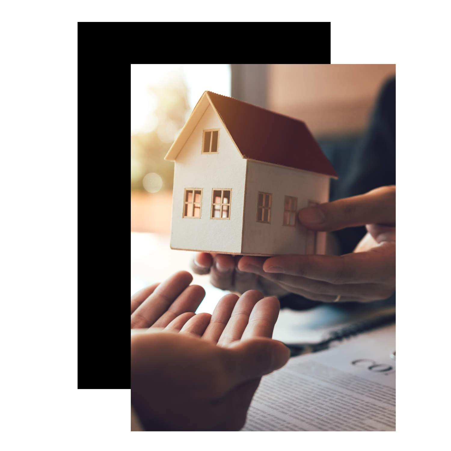 Two people exchanging a small model house during a real estate or home buying discussion.
