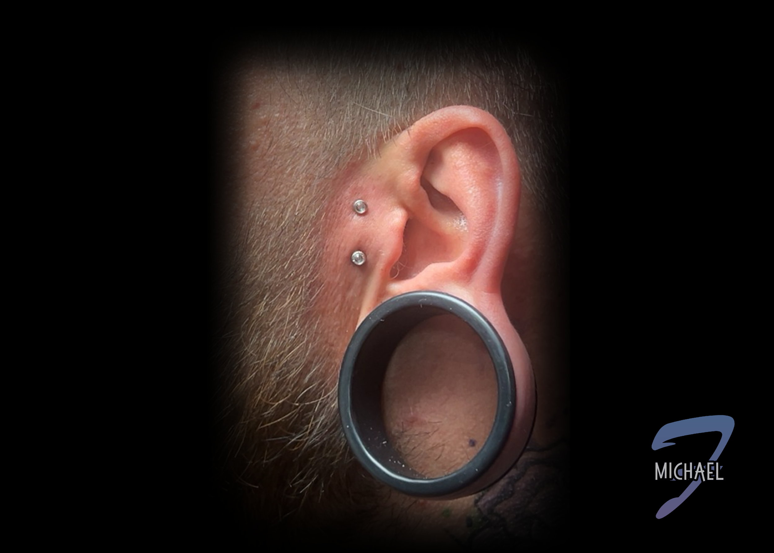 A Dermal tragus anchor on a mans face, done by piercer Michael Fontan.