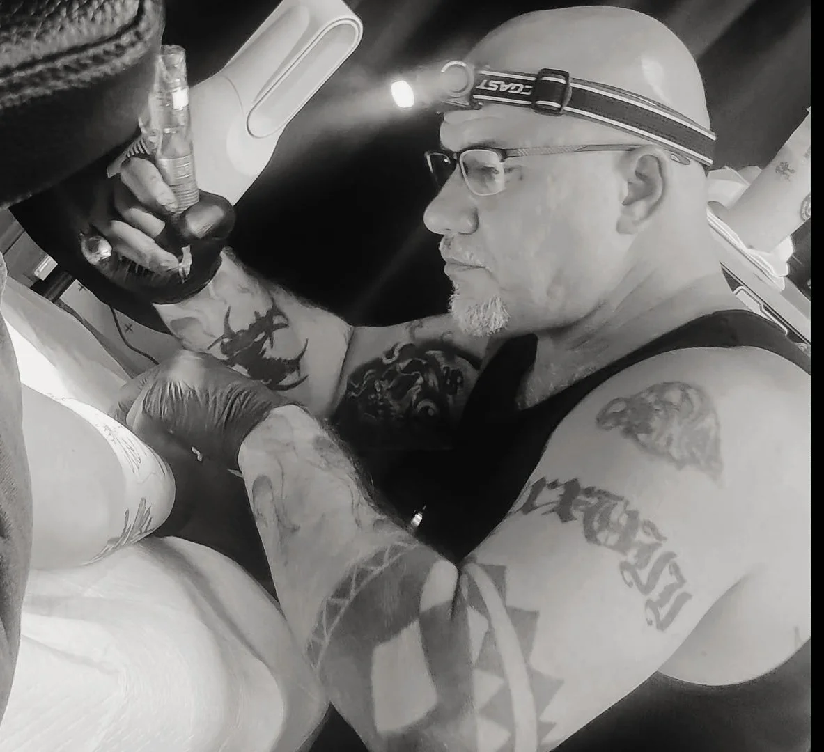 Tattoo artist Seneca Hopps in studio with his skull with sword black and grey tattoo piece.