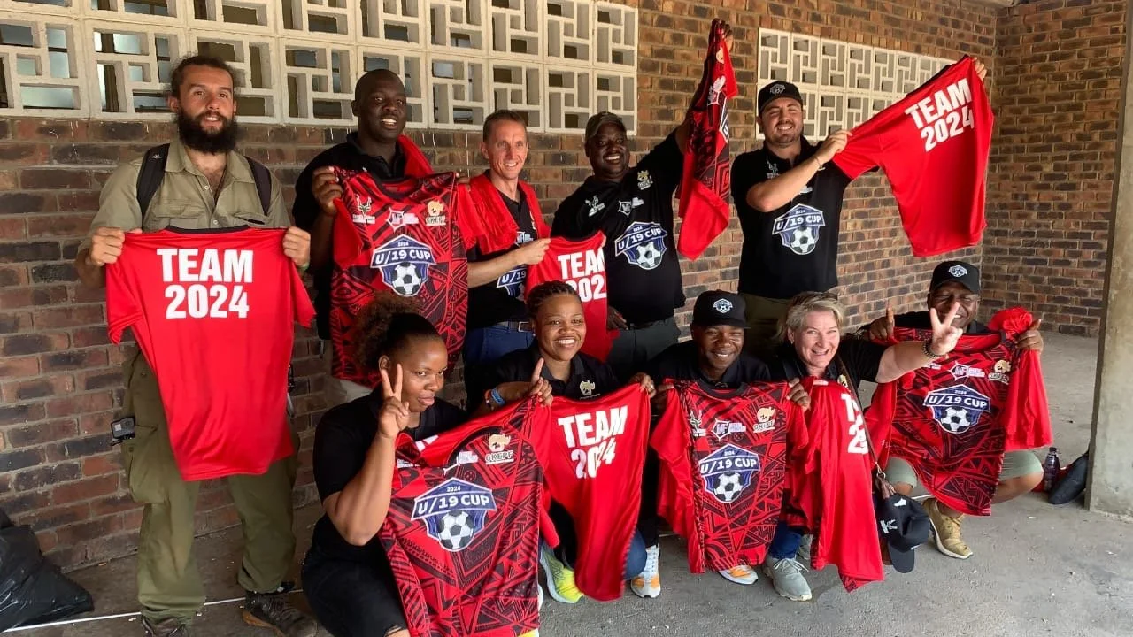 A Group of people holding red soccer jerseys and banners.