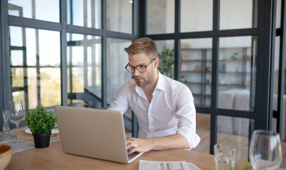 Man in glass office working on computer. Image for Book Architect Level 3 Publishing Package.