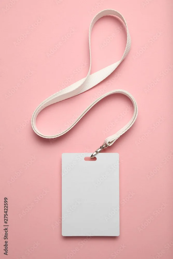 A white lanyard with a blank white identification badge attached, lying on a pink background.