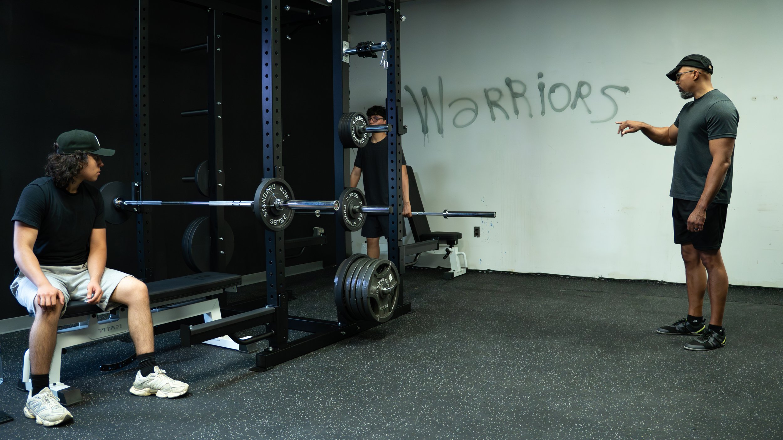 Man coaching youth lifting weights in weight room
