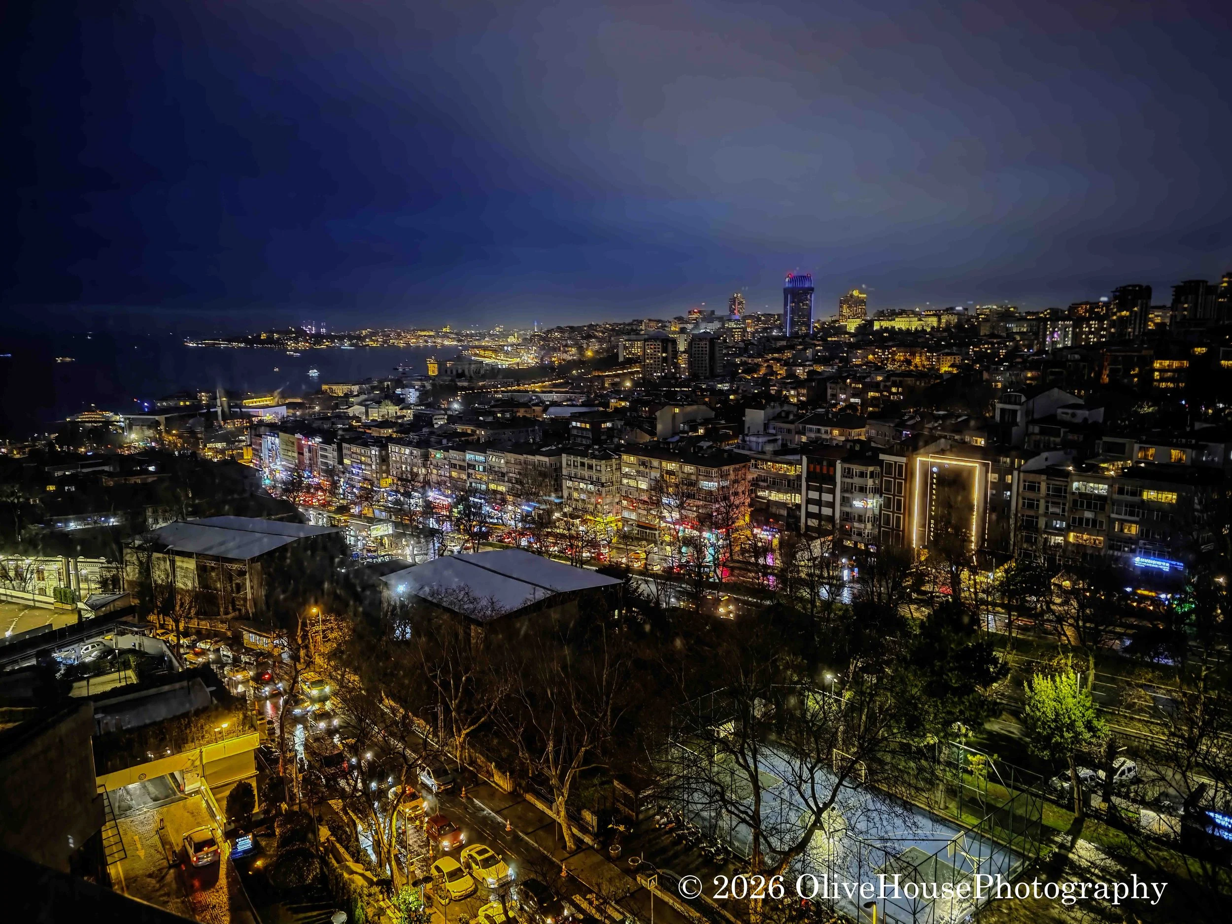 Nighttime panoramic view of Istanbul, Turkey, featuring the historic city landscape and the Bosphorus strait in the distance. 