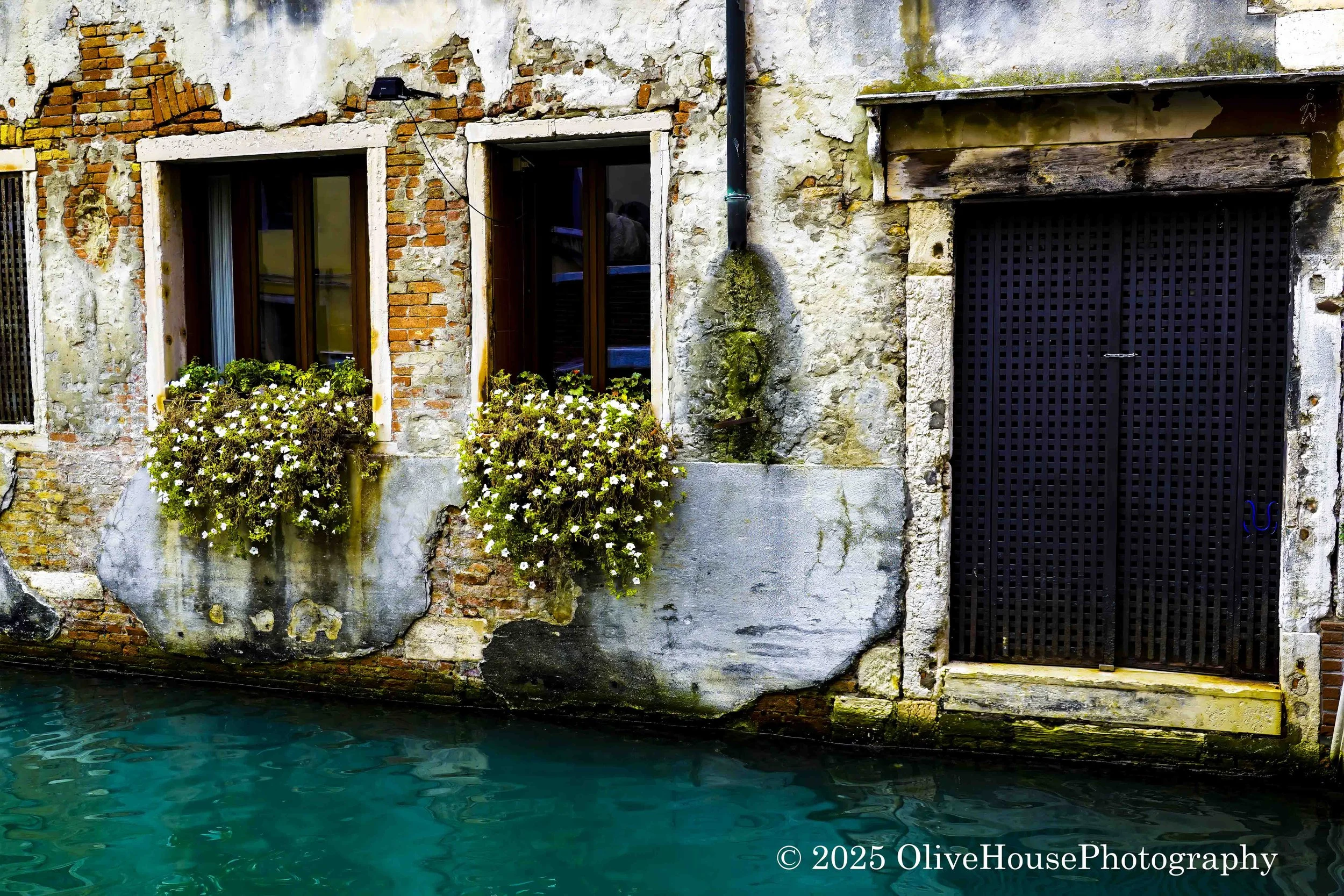Aged, weathered architecture with exposed brickwork and crumbling plaster on a canal in Venice, Italy. 
